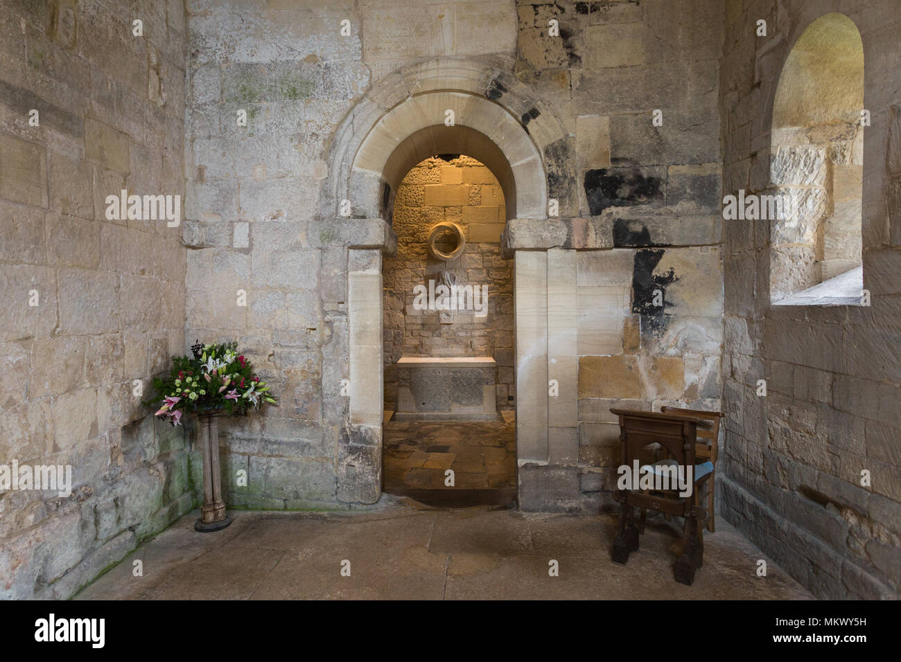 Vista interna attraverso l'arcata in pietra del religioso altare nel presbiterio entro l'antica San Lorenzo è la Chiesa, Bradford-on-Avon, Wiltshire, Regno Unito. Foto Stock