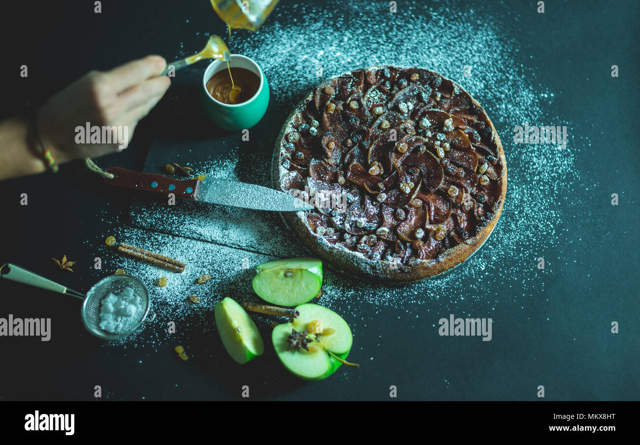 Torta di mele con crema al caramello sulla tavola nera con zucchero in background e Apple Foto Stock