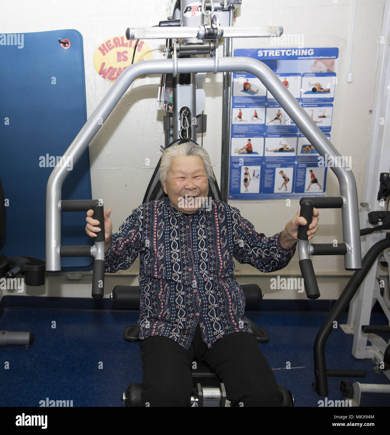 91 enne donna cinese continua a montare su macchine ginniche a un senior center sulla Lower East Side di Manhattan, New York City. Foto Stock