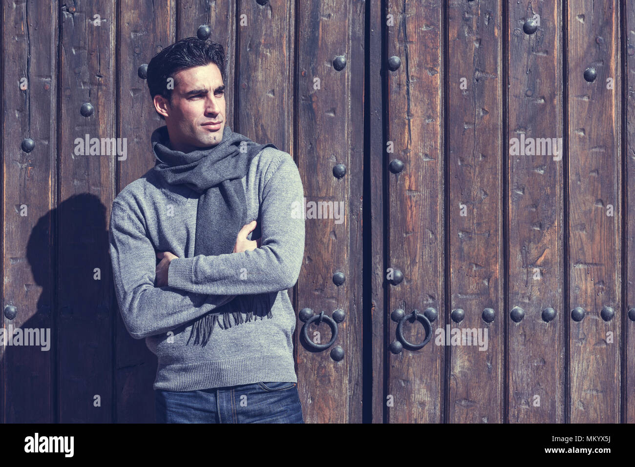 Uomo bello indossare abbigliamento invernale in background in legno.  Giovane maschio con swater e sciarpa Foto stock - Alamy
