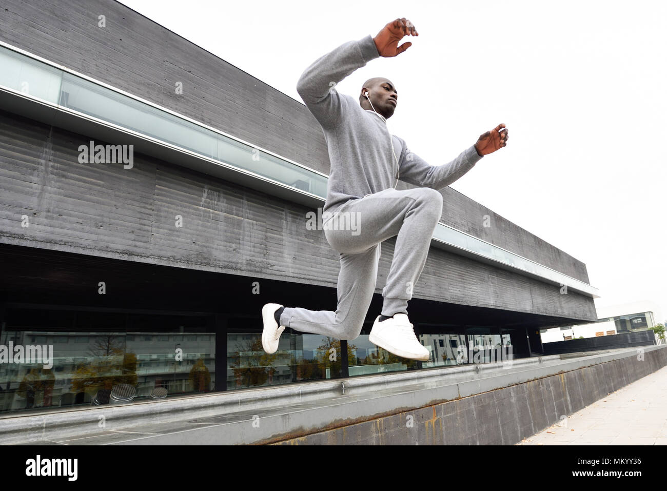 Uomo nero saltando in background urbano. Maschio a fare allenamento all'aperto. Foto Stock