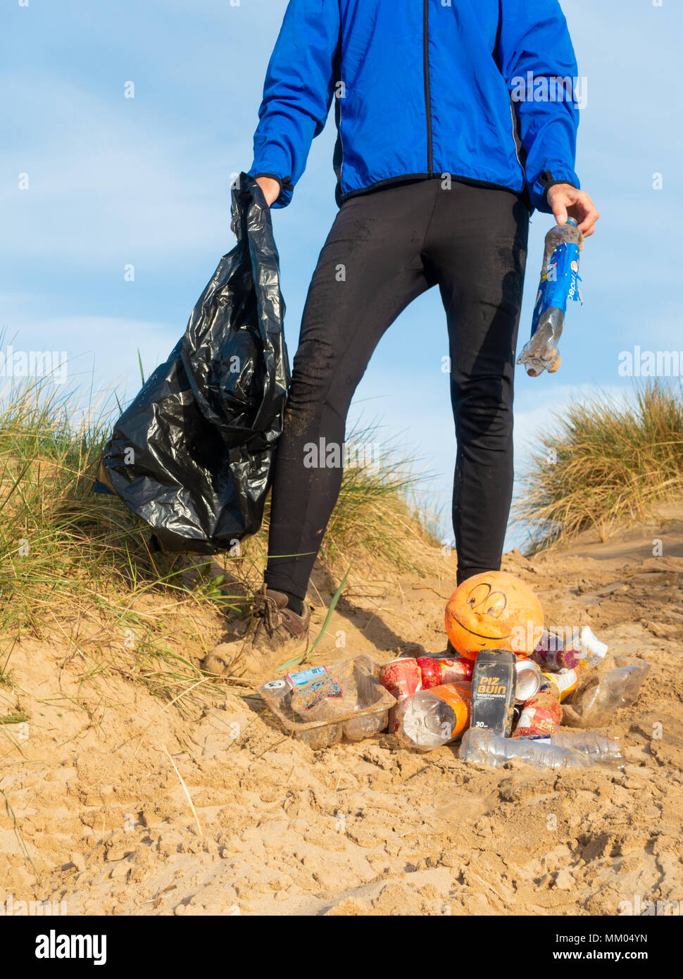 Un pareggiatore Plogging (prelievo di lettiera durante il jogging) sulla sua corsa mattutina attraverso le dune di sabbia.UK Foto Stock