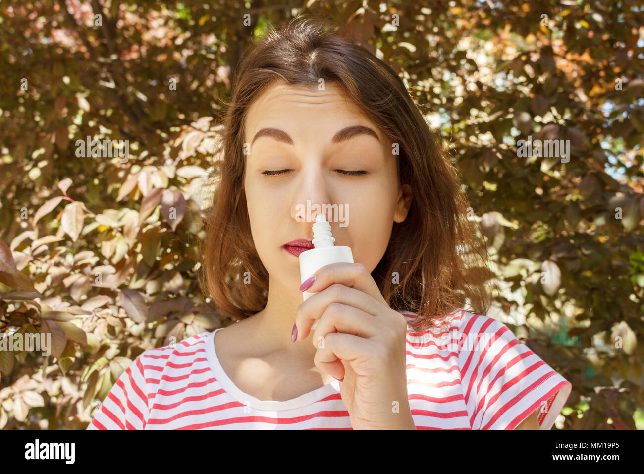 Ragazza gocciolamenti naso chiuso da allergia. Donna con Apparato Respiratorio Spray per naso in fioritura primaverile. Ritratto di una donna con problemi respiratori da un Foto Stock