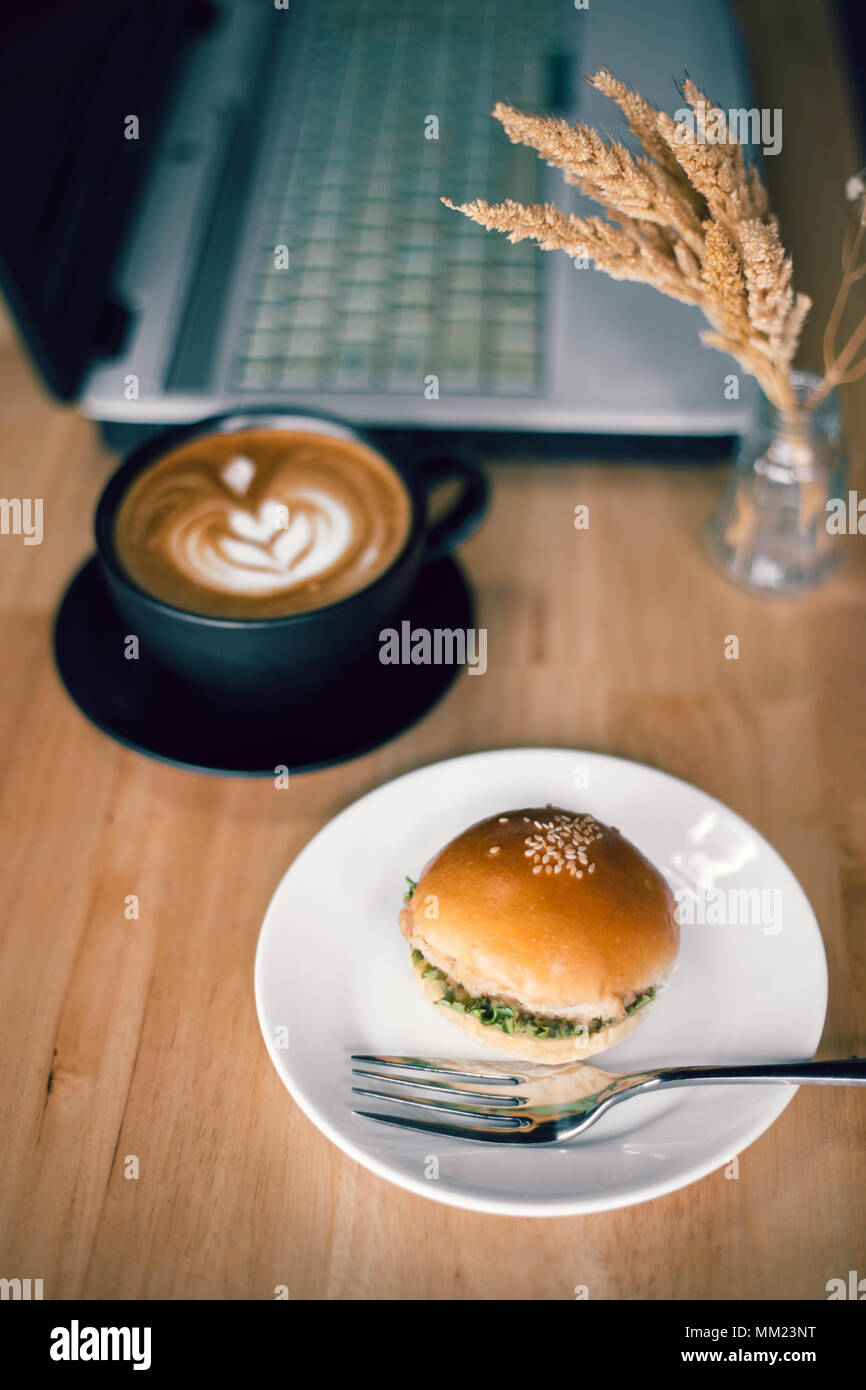 Mini hamburger con tazza di caffè e computer portatile sul tavolo Foto Stock