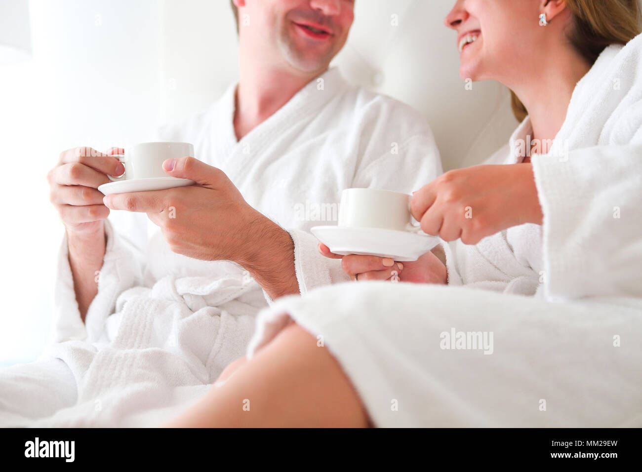 L uomo e la donna in accappatoio di bere il caffè nel letto. La colazione del mattino Foto Stock