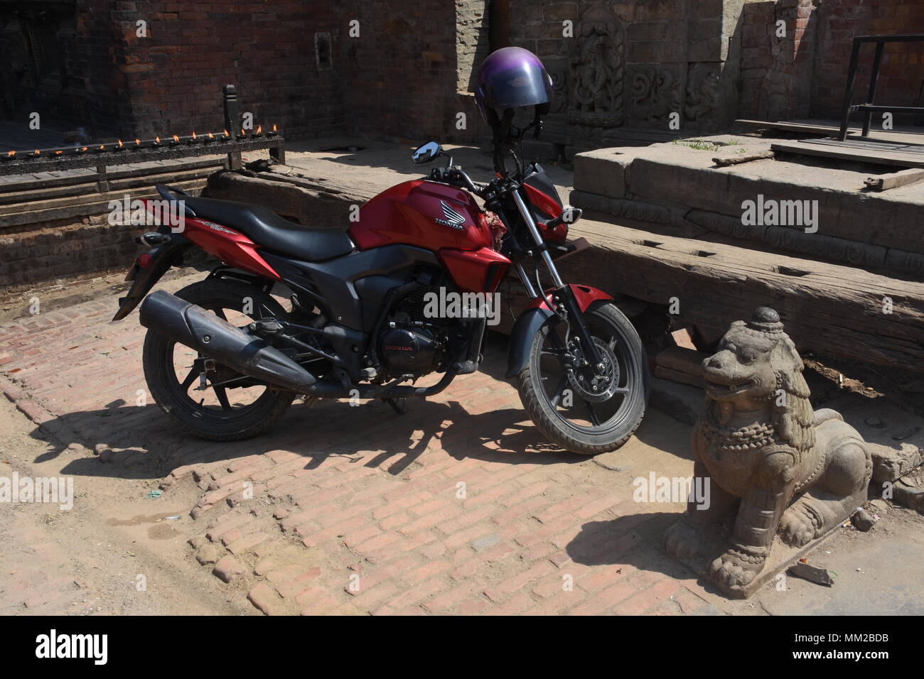 Bhaktapur, Nepal - Marzo 23, 2018: motociclo moderna e antica statua di Lion Foto Stock