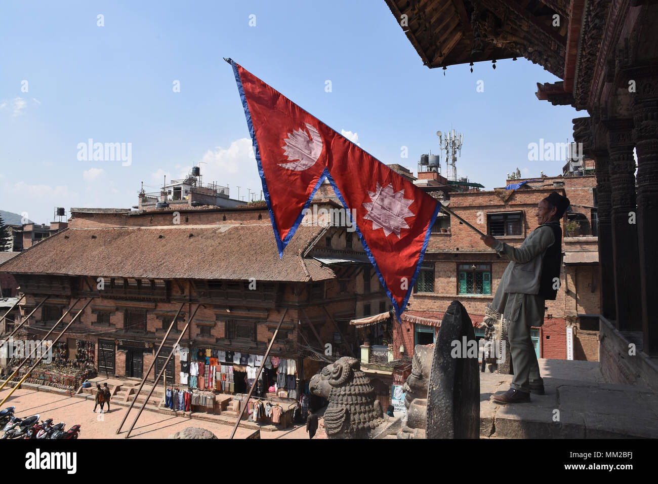 Bhaktapur, Nepal - Marzo 23, 2018: uomo sventola una bandiera Nepalese sul tempio Nyatapola Foto Stock