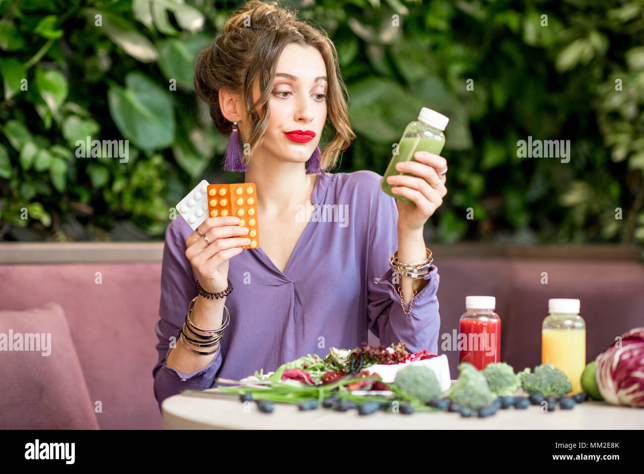 Donna con le pillole e cibo sano Foto Stock