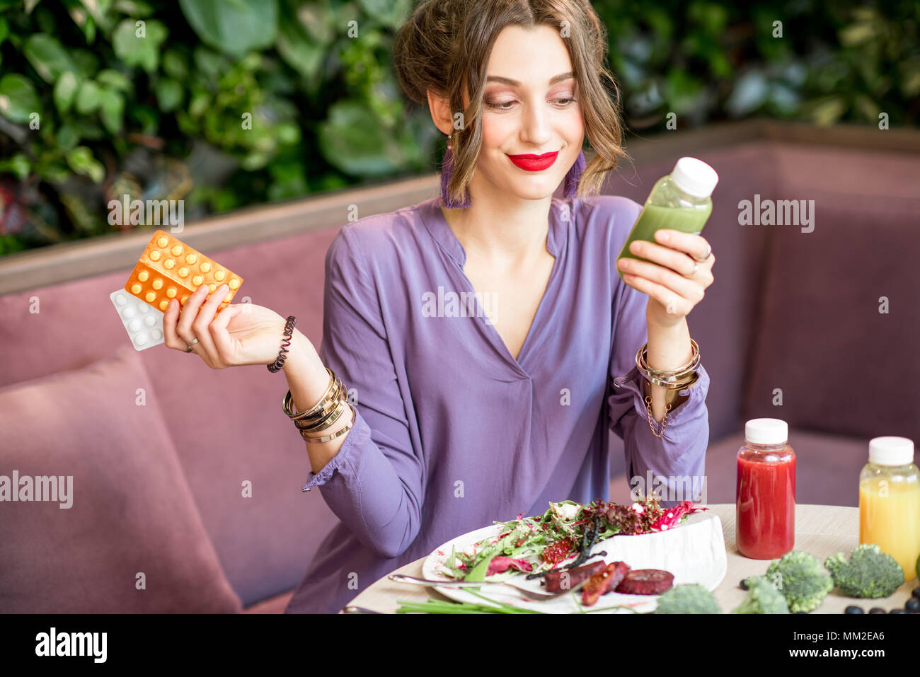 Donna con le pillole e cibo sano Foto Stock