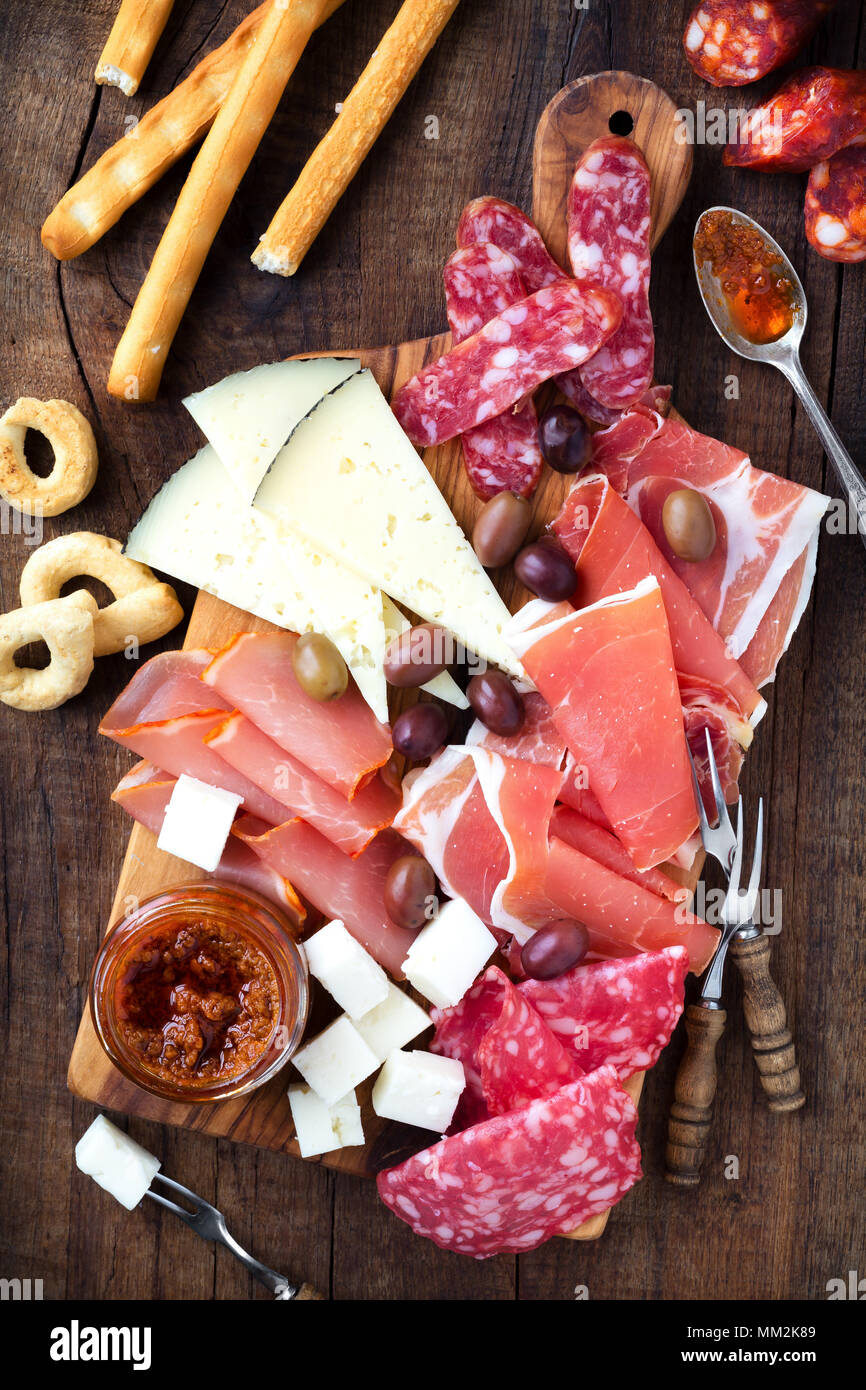 Salumi e formaggi piatto di tapas tradizionali spagnole - chorizo, salsichon, jamon serrano, lomo e fette di formaggio di capra - servita su cinghiale in legno Foto Stock