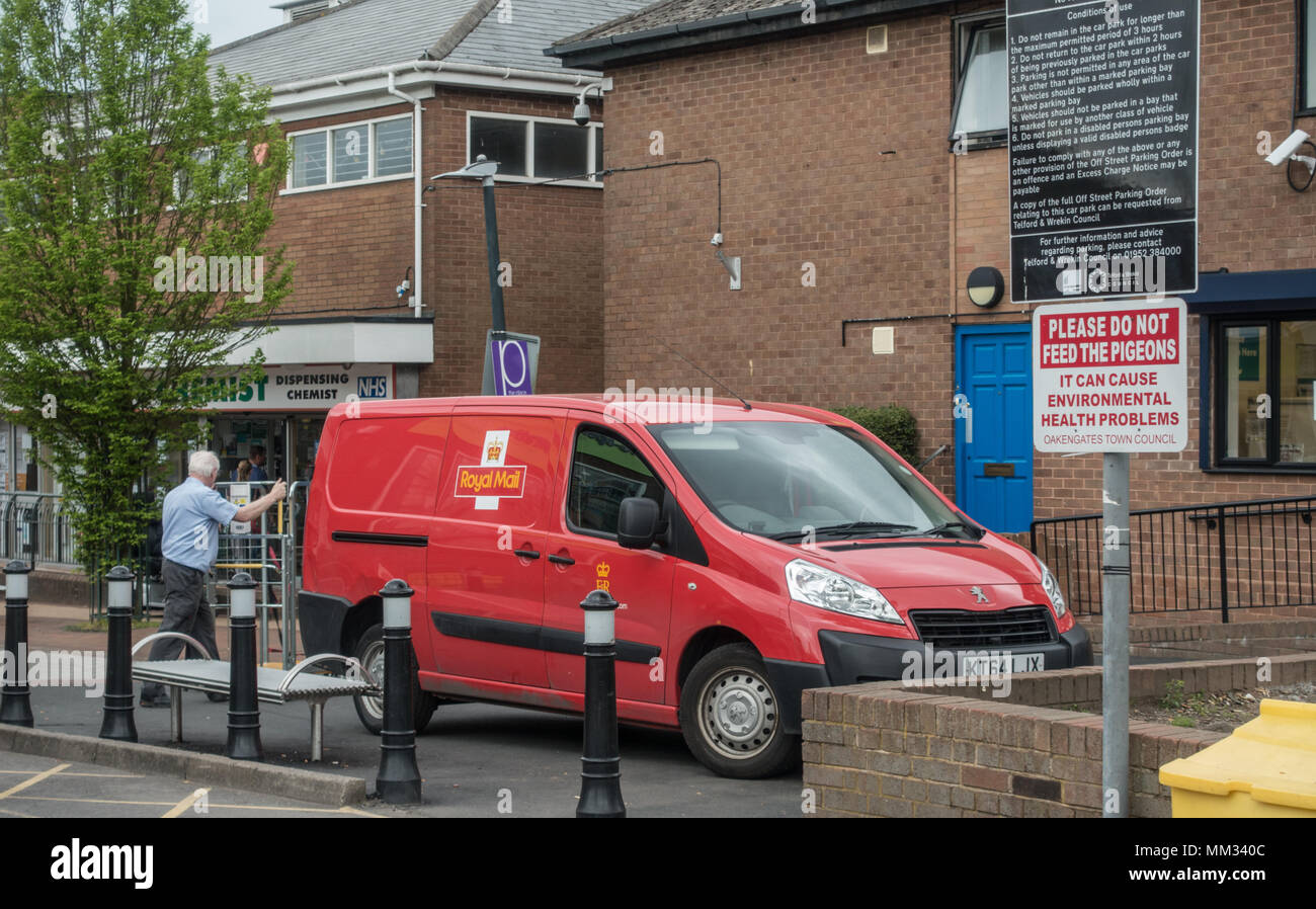 Un postino caricando il suo furgone con pacchi dal locale ufficio postale, mentre parcheggiato sul marciapiede in un area pedestrain Foto Stock