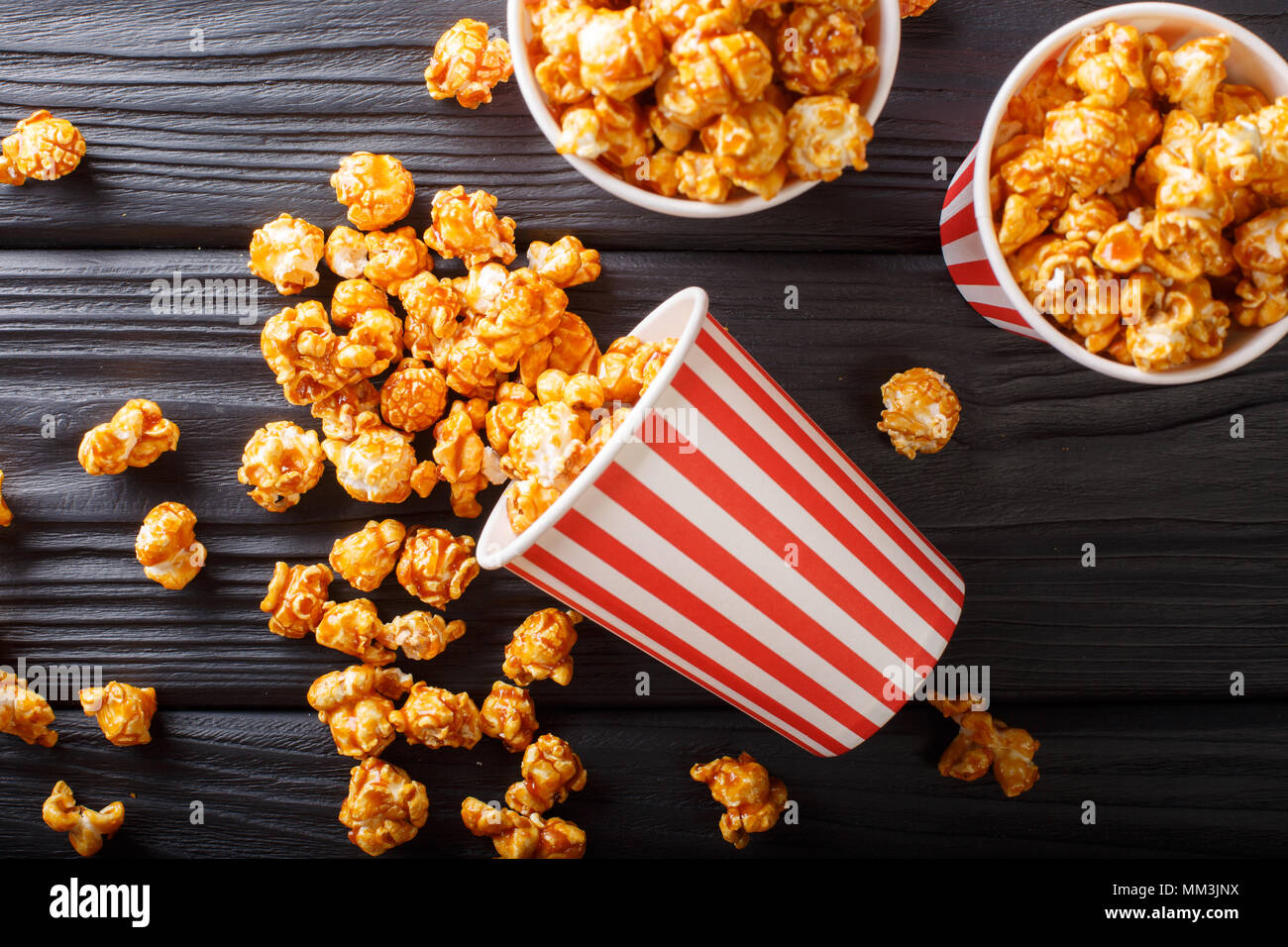 Dolce caramello popcorn in bicchieri di carta di close-up sulla tavola nera. parte superiore orizzontale vista da sopra Foto Stock