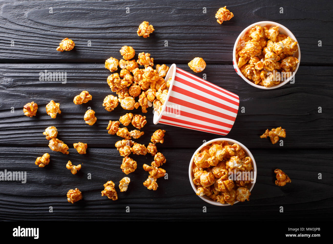 Scatole con caramello wweet popcorn, sfondo nero, snack per il cinema closeup. Parte superiore orizzontale vista da sopra Foto Stock