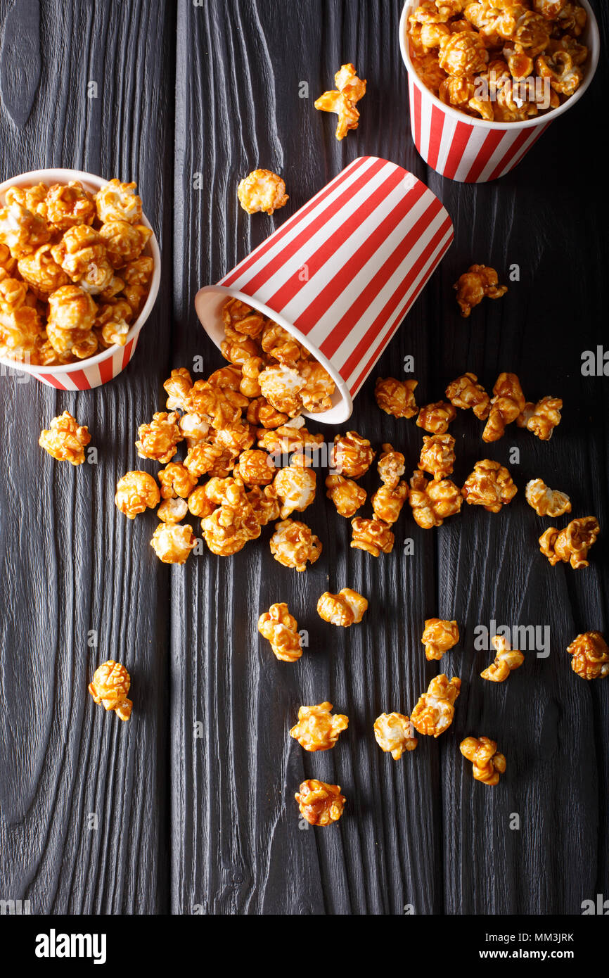 Scatole con caramello wweet popcorn, sfondo nero, snack per il cinema closeup. Verticale in alto vista da sopra Foto Stock