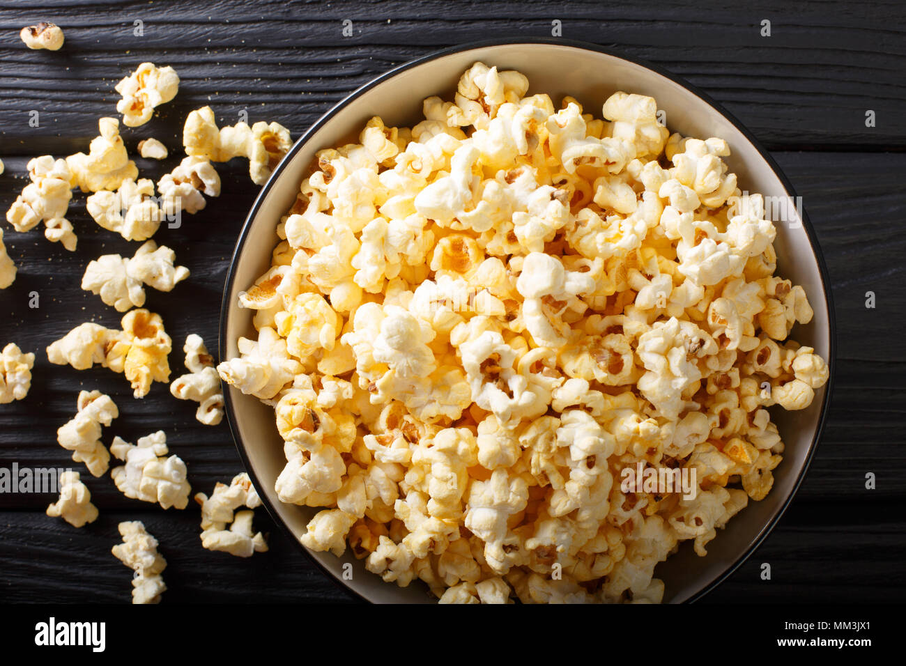 Popolari: snack salati popcorn con il formaggio Cheddar e il parmigiano in una ciotola vicino sul tavolo. Parte superiore orizzontale vista da sopra Foto Stock