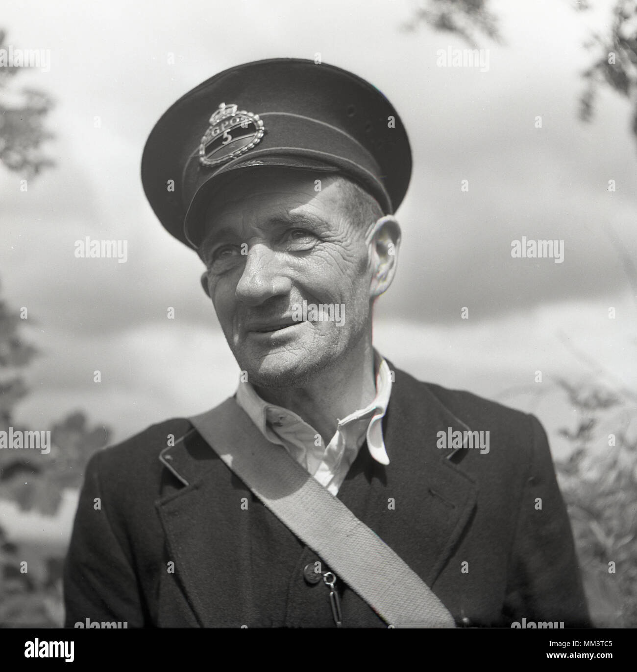 Degli anni Cinquanta, storico ritratto di un GPO maschio lavoratore esterno in uniforme e indossando il cappuccio badge, Irlanda del Nord, Regno Unito. Foto Stock