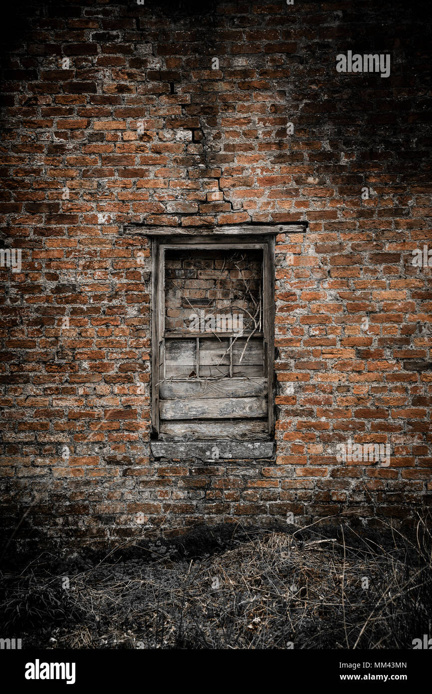 Rovinato e intavolato vetro rotto in un antico muro in mattoni a vista Foto Stock