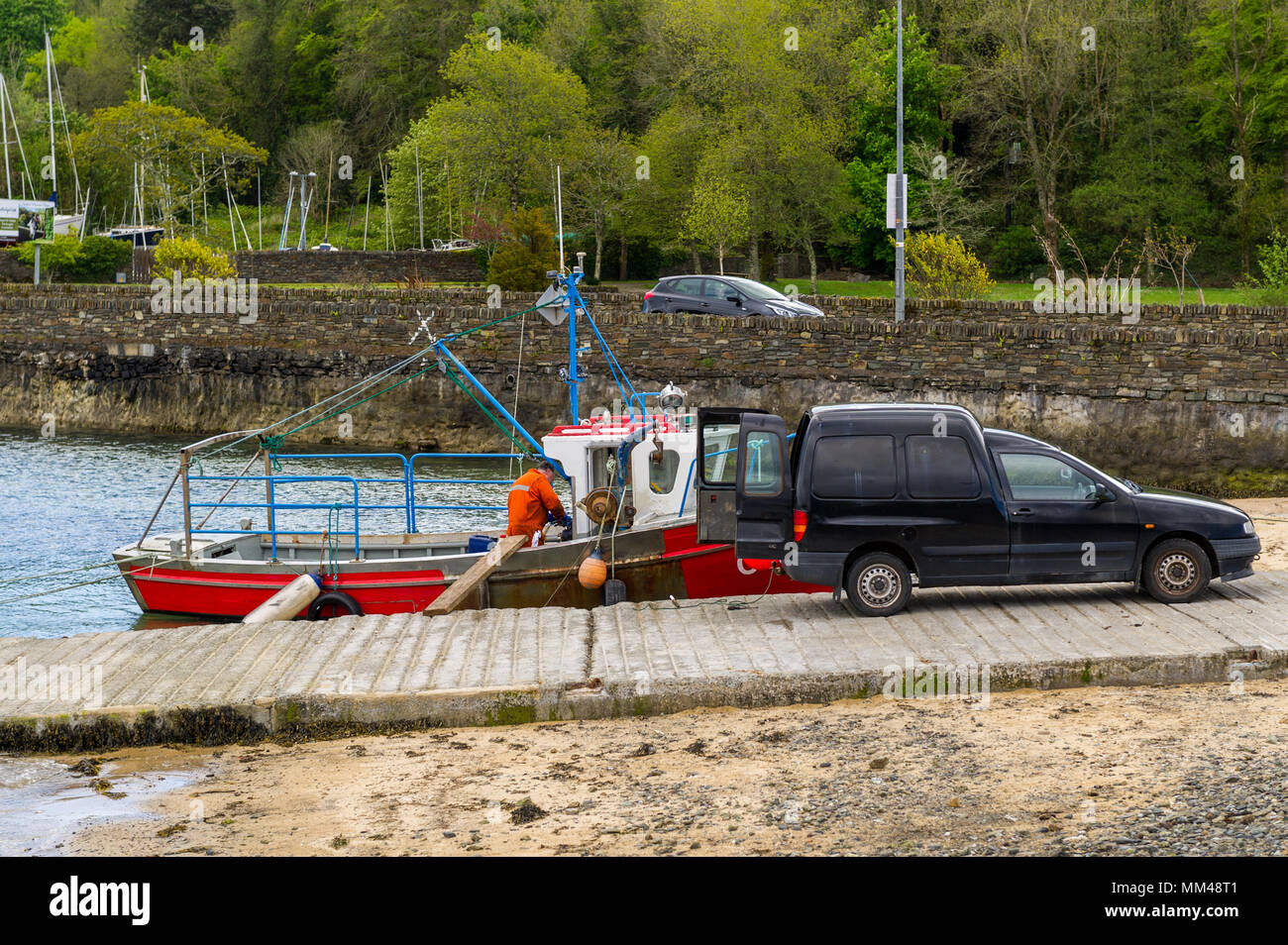Fisherman dipinge la sua barca che è legata a una sorta di scivolo in Bantry, County Cork, Irlanda. Foto Stock