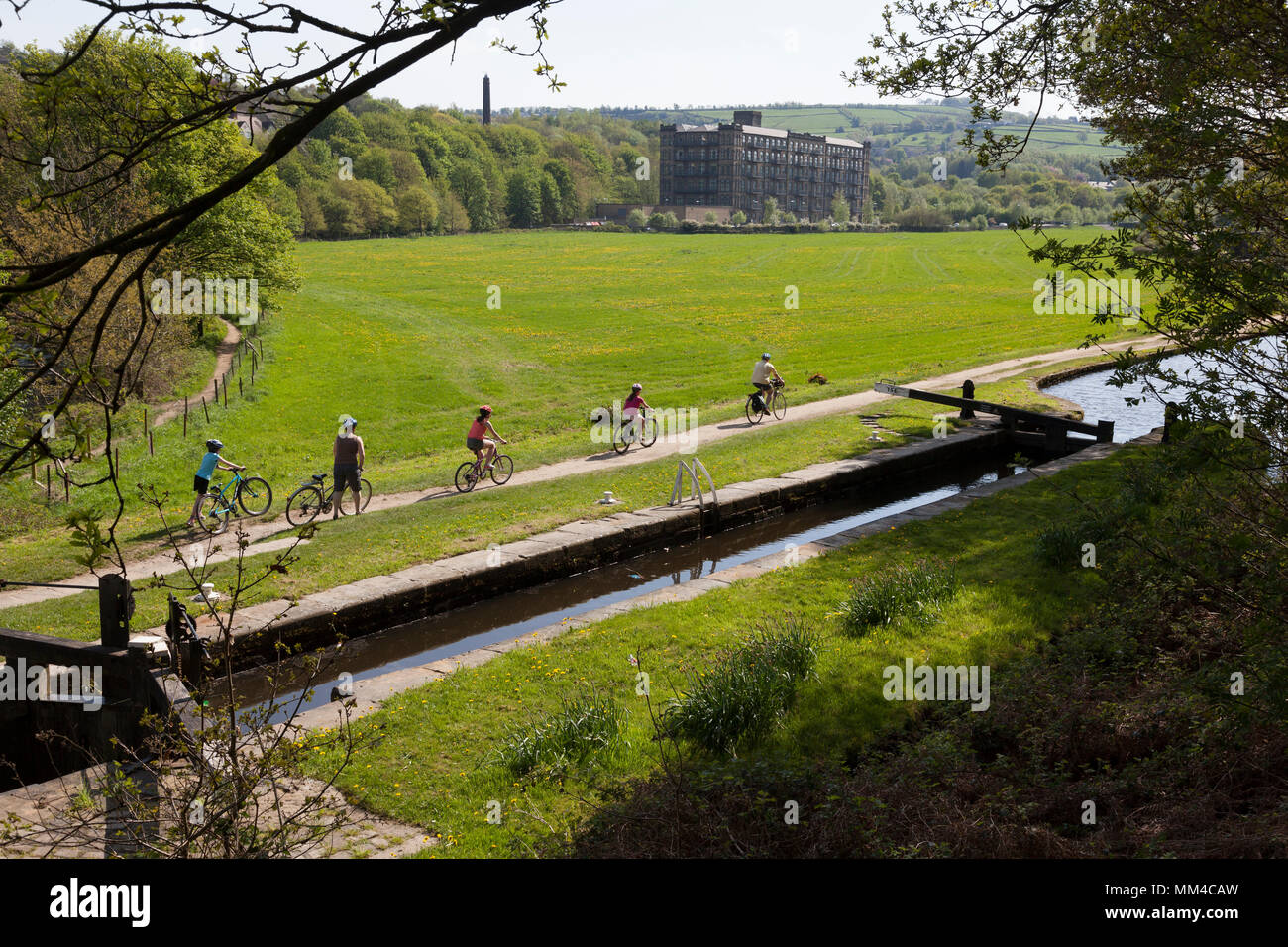 Famiglia passato ciclismo serratura al ponte di Scarwood su The Huddersfield stretto canale a Linthwaite, West Yorkshire Foto Stock