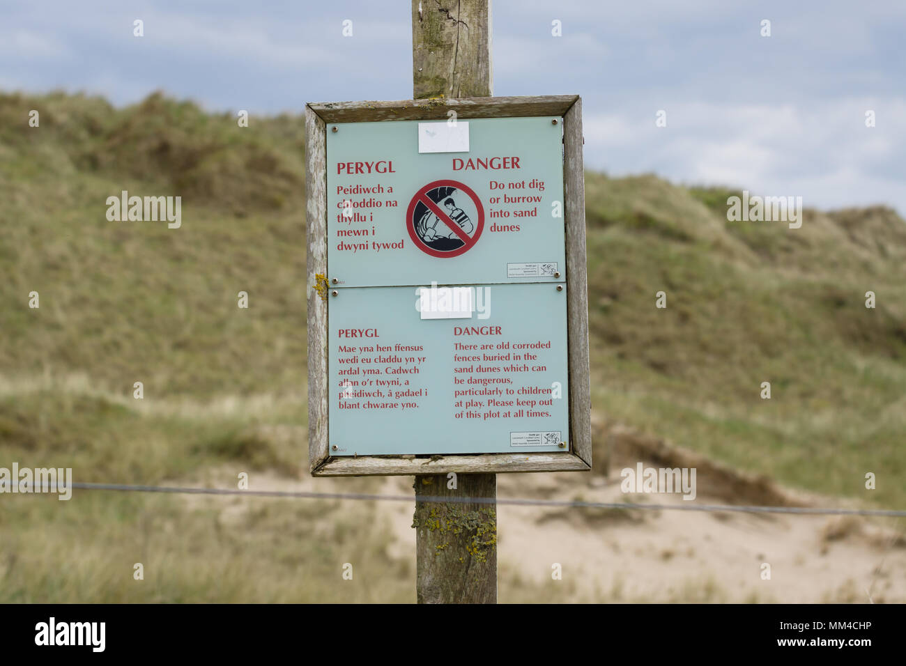 Segno avvertenza non scavare o scavano nella dune di sabbia a causa del pericolo di crollo postato da risorse naturali del Galles sulla spiaggia Harlech nel Galles del Nord Foto Stock