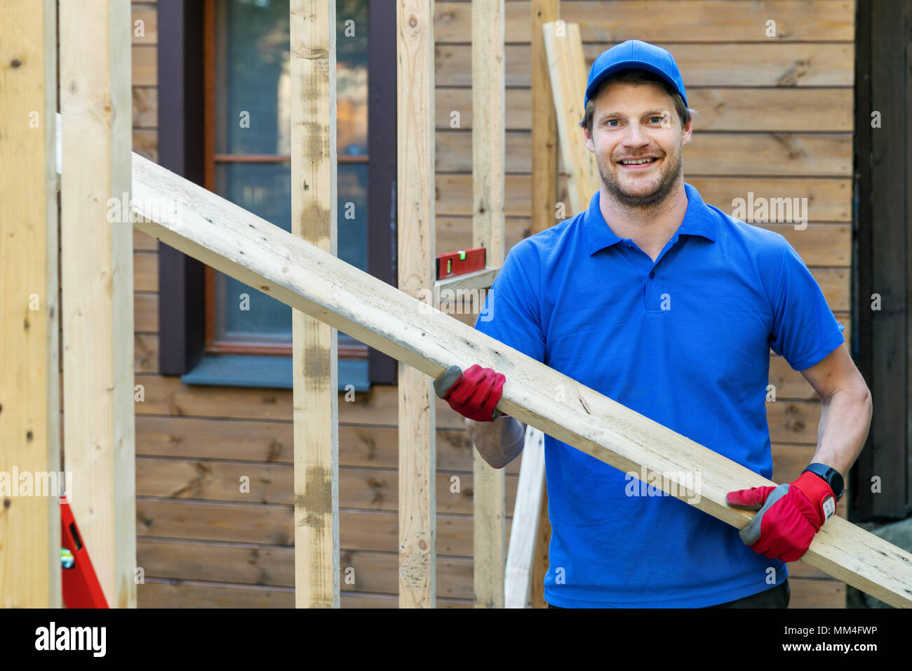 Lavoratore con asse di legno in mani al sito in costruzione Foto Stock