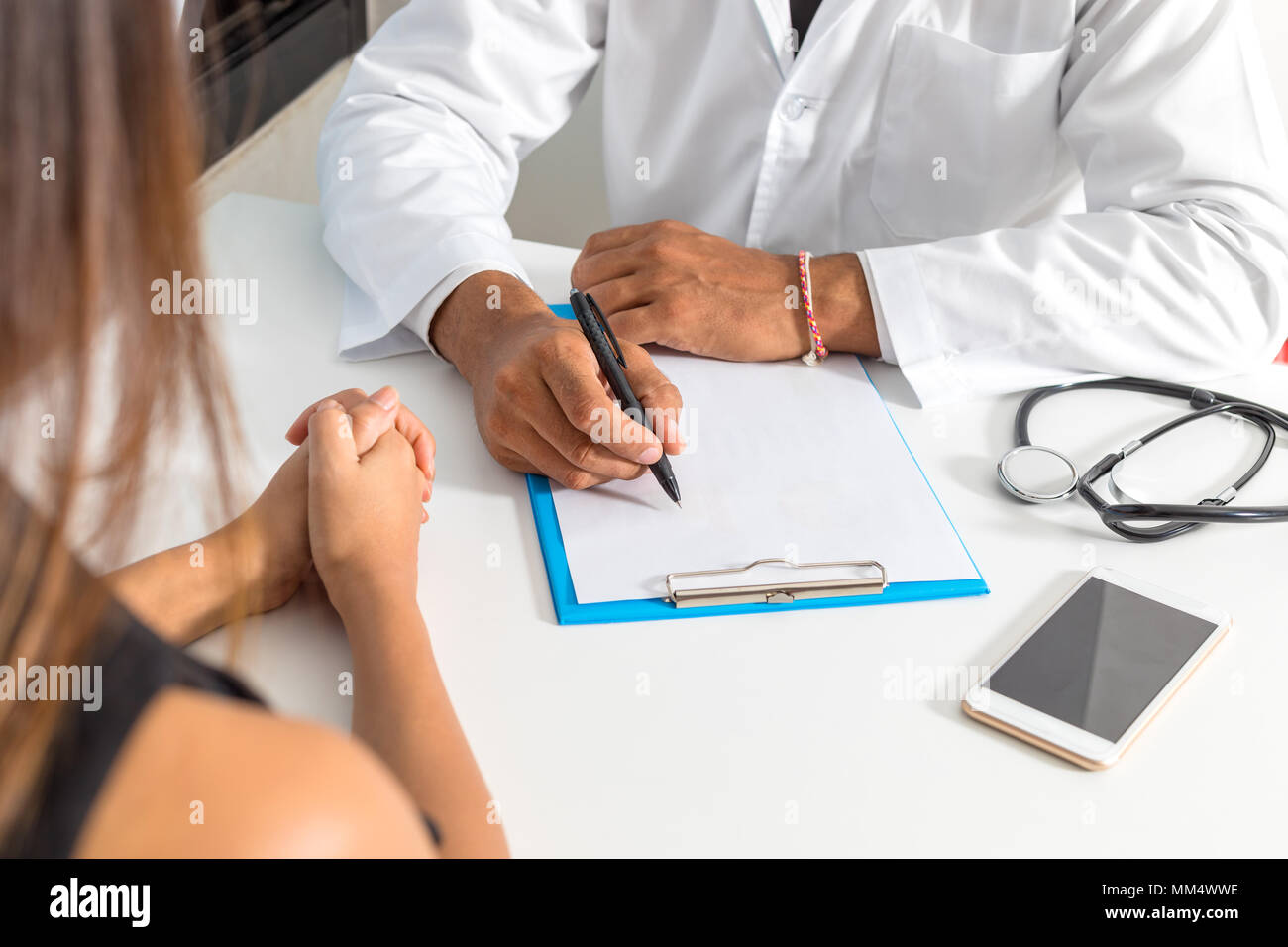 Il medico e il paziente stanno discutendo circa la diagnosi. Medico tenendo uno stetoscopio e prendere appunti. Foto Stock