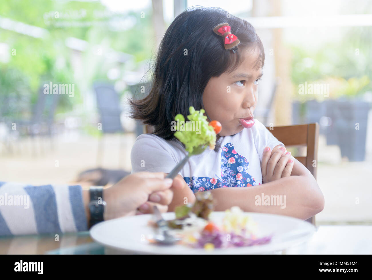 Bambino asiatico ragazza con espressione di disgusto contro le verdure nel ristorante, rifiutando il concetto di cibo Foto Stock