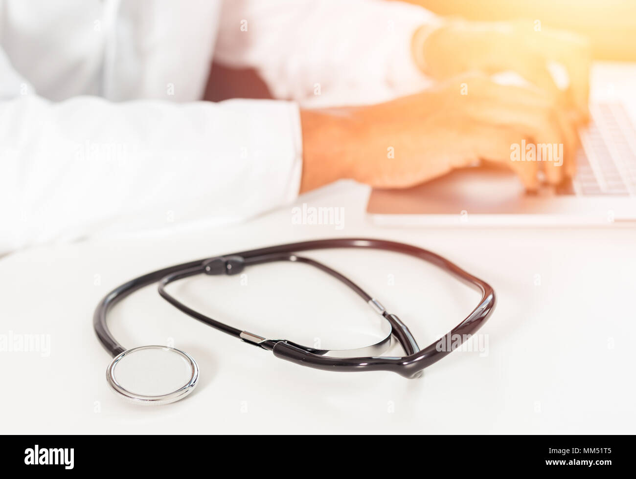 Immagine sfocati di un medico che lavorava con computer portatile in area di lavoro medico ufficio come concetto con uno stetoscopio Foto Stock