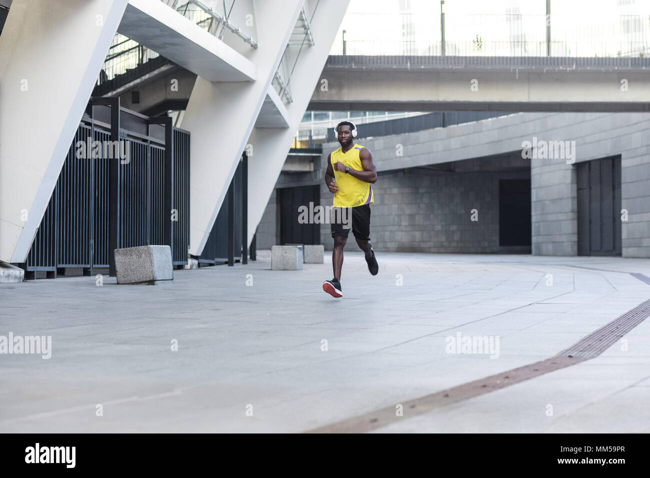 Bello afro-americano di formazione di runner e jogging in un giorno di estate all'aperto che indossa il colore giallo sportswear Foto Stock