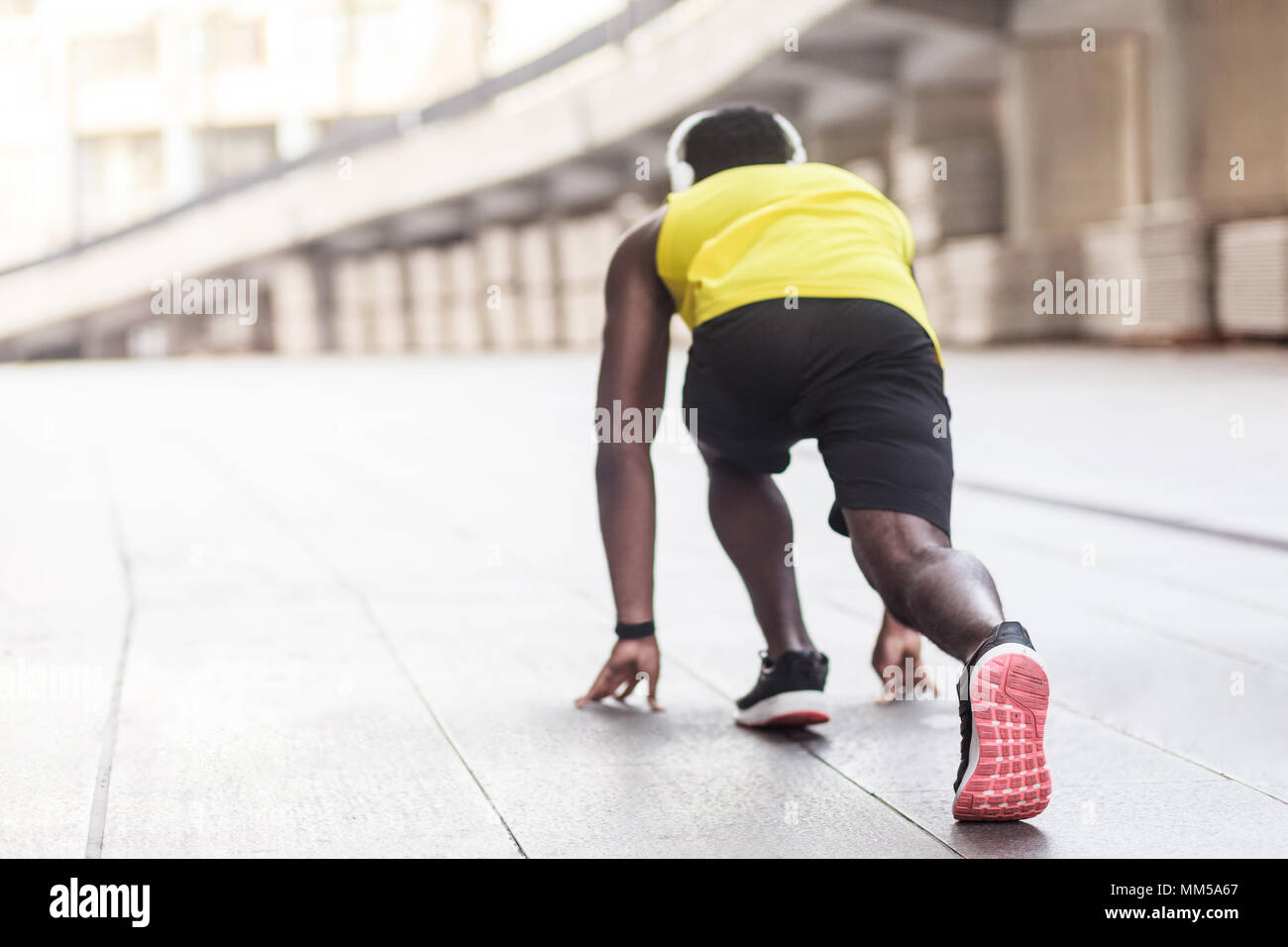 Vista della colonna vertebrale. Atleta africana in esecuzione di posa di inizio. Colpo all'aperto, la mattina. Primavera o estate Foto Stock