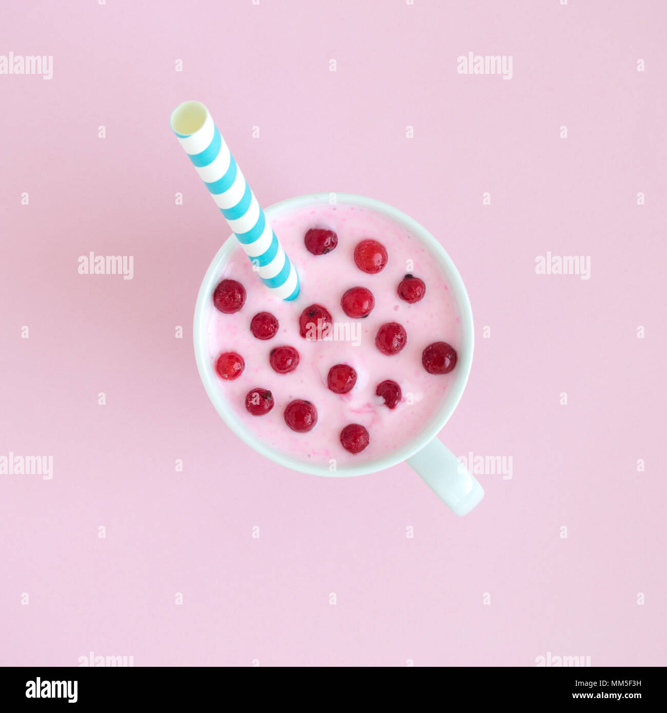 Piatto di laici smoothie con ribes rosso di bacche e cannuccia contro di rosa pastello minima di sfondo concetto creativo. Foto Stock