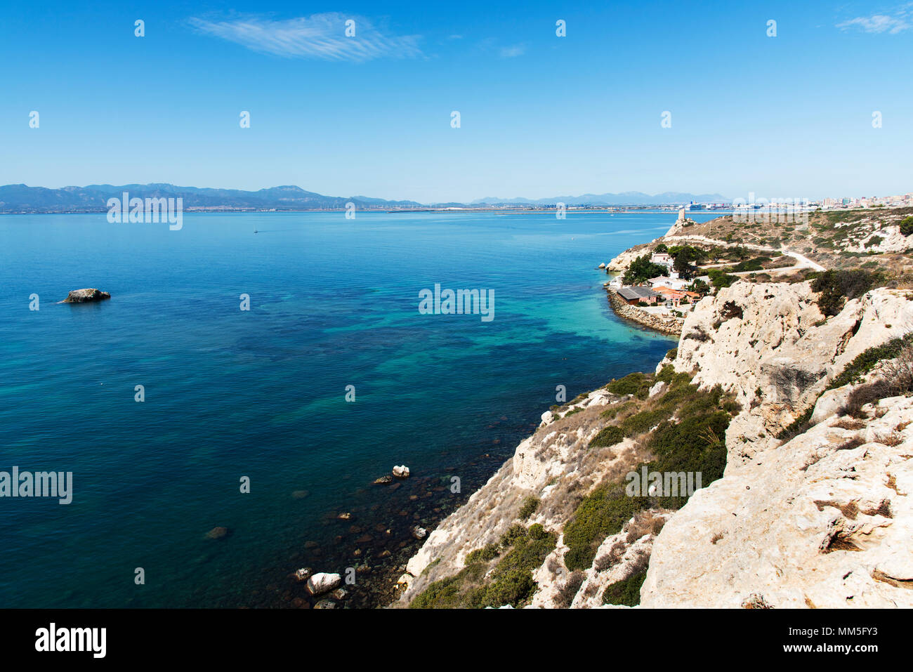 Una vista della costa di Sant Elia a Cagliari, Sardegna, evidenziando il prezzemolo torre sulla destra e il porto di Cagliari in background Foto Stock