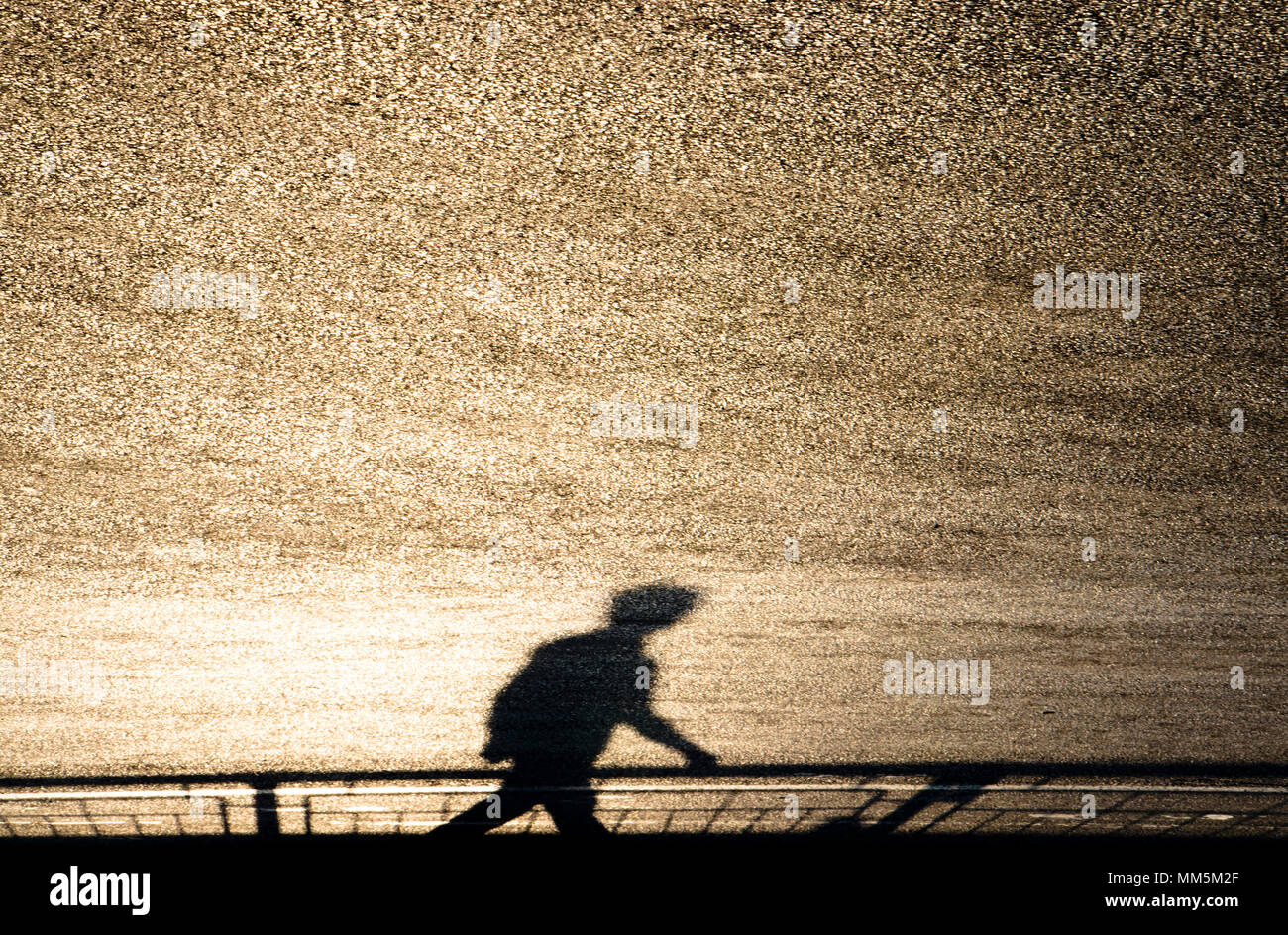 Defocalizzata sfocata ombra silhouette di un uomo che cammina sulla strada lucido su sunset Foto Stock