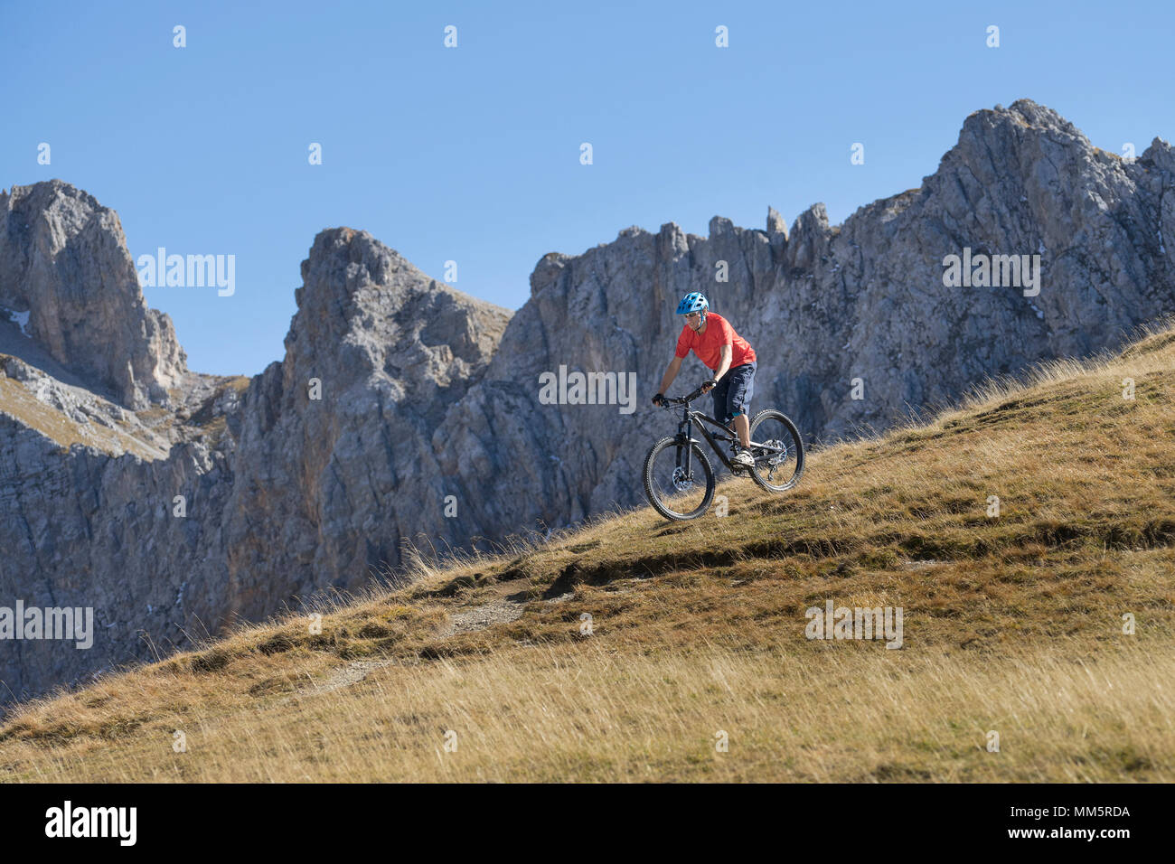 Mountain Biker cavalcare giù per la collina nel paesaggio alpino, Tirolo, Austria Foto Stock