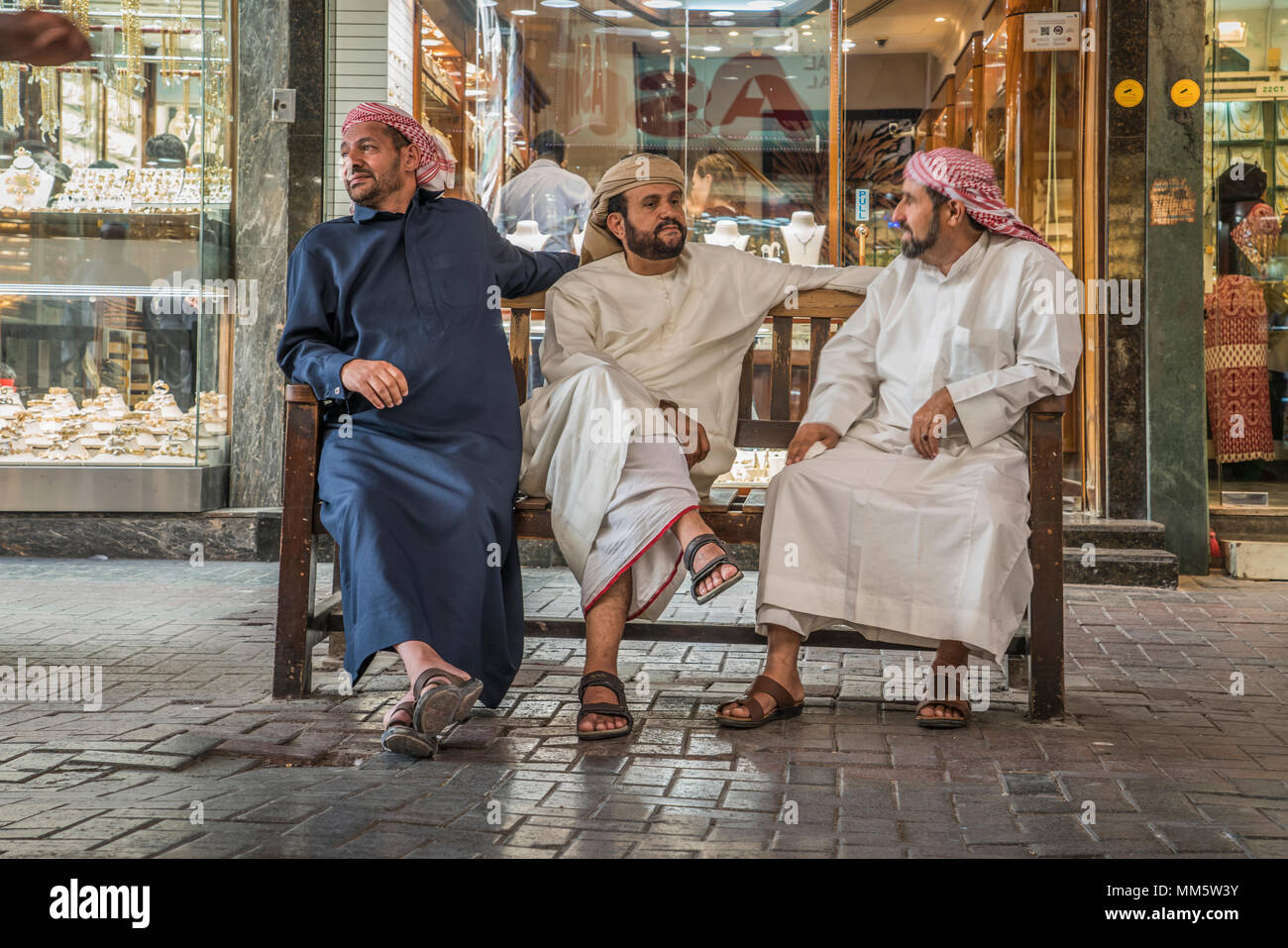 Un gruppo di uomini in arabo abito tradizionale conversando nel mercato dell'oro della città vecchia souk di Dubai, UAE, Medio Oriente. Foto Stock