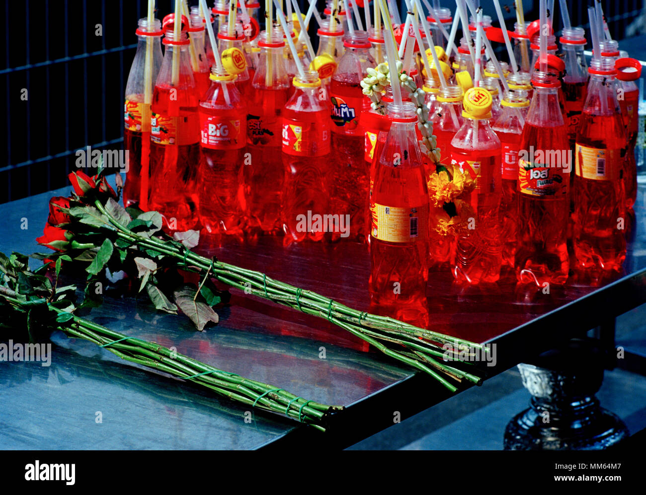 Still Life di bottiglie di rosso e di rosa fiori di Trimurti statua Dio dell amore al mondo centrale di Bangkok in Thailandia del sud-est asiatico in Estremo Oriente. Viaggiare Foto Stock