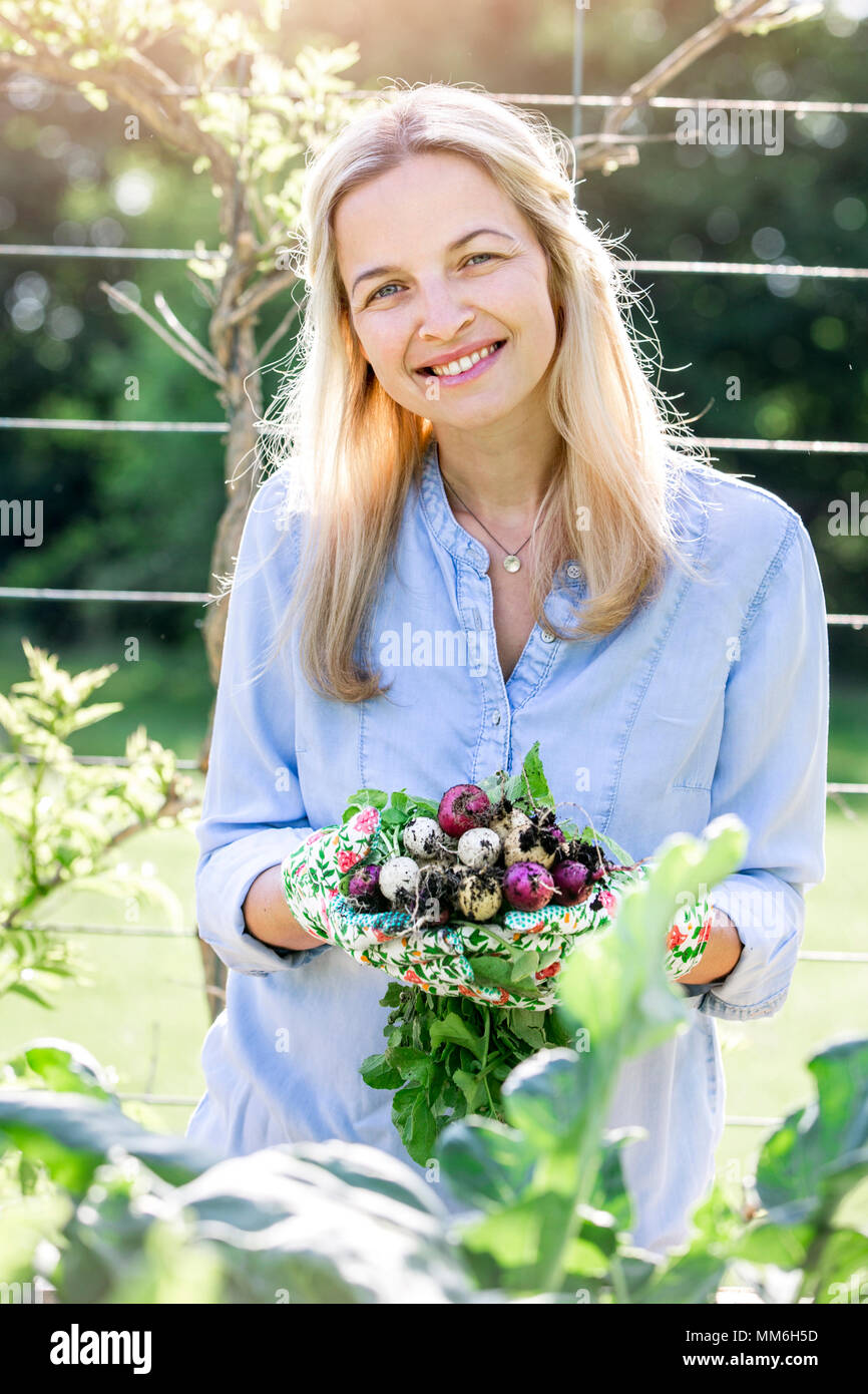 Giardinaggio - Donna è azienda bio freschi ravanelli nelle sue mani Foto Stock