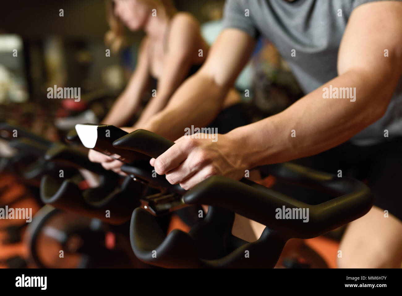 Close-up delle mani di un uomo mountain bike in palestra, esercitando le gambe facendo cardio allenamento ciclismo biciclette. Matura in una classe di filatura di indossare abbigliamento sportivo. Foto Stock