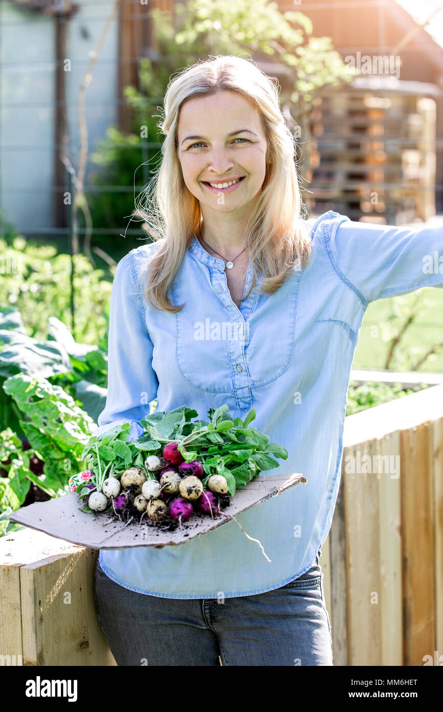 Giardinaggio - Donna è azienda bio freschi ravanelli nelle sue mani Foto Stock