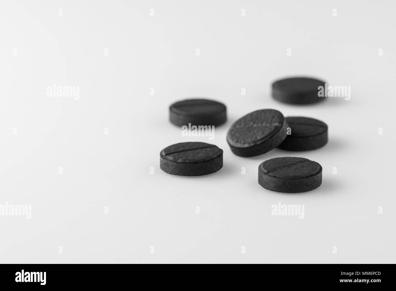 Molti medici nero carbone attivo pillole su sfondo bianco. Isolato Foto Stock