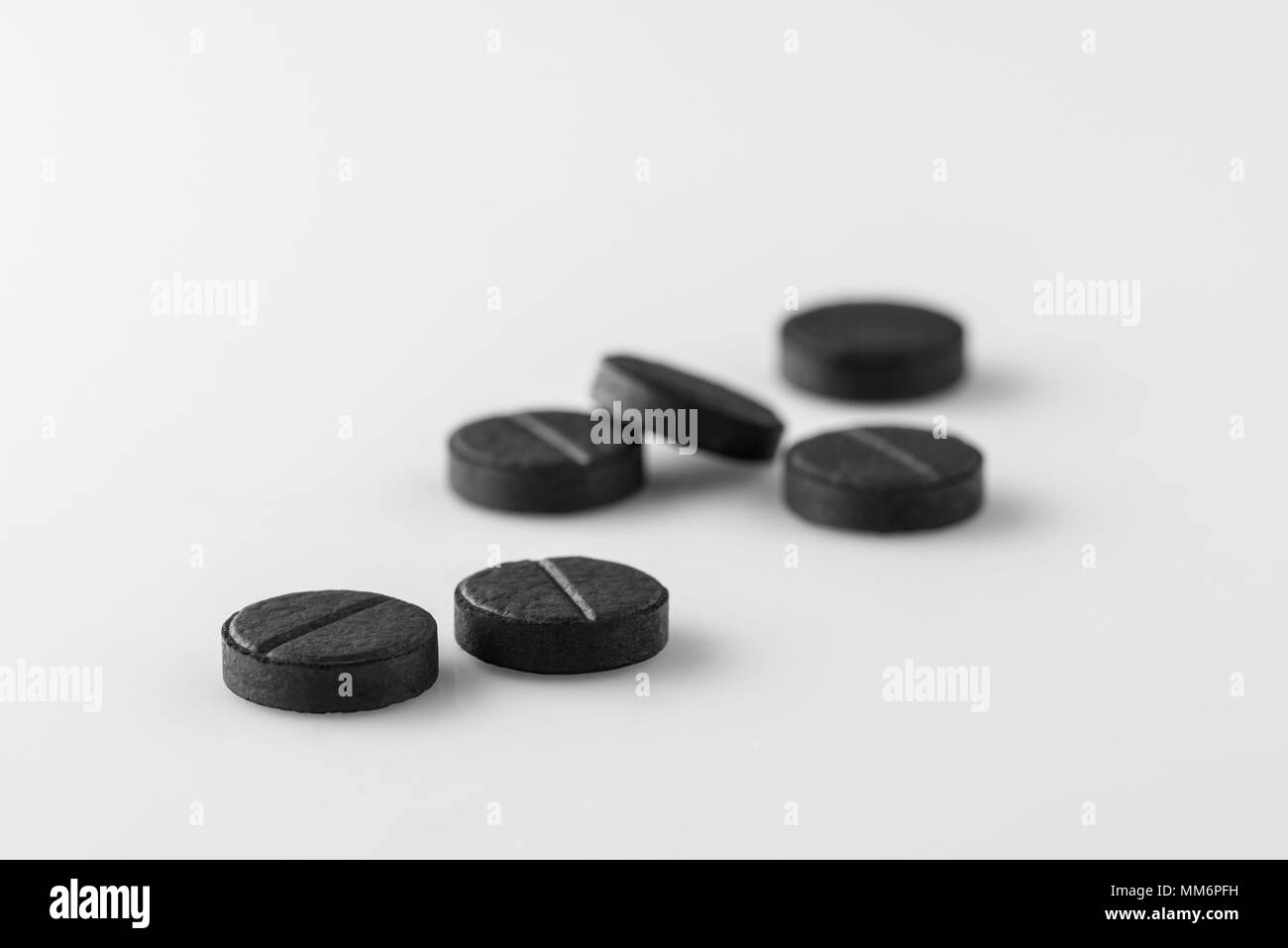 Molti medici nero carbone attivo pillole su sfondo bianco. Isolato Foto Stock