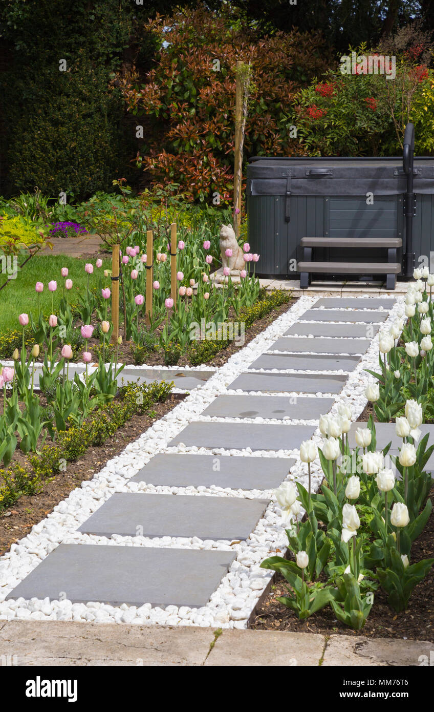 Symphony vetrificati di pavimentazione in lastre formano un percorso che conduce a una vasca con acqua calda Tulipa "diamante rosa' e Tulipa "Coquette' su entrambi i lati. Credits: Design by Zinn Foto Stock