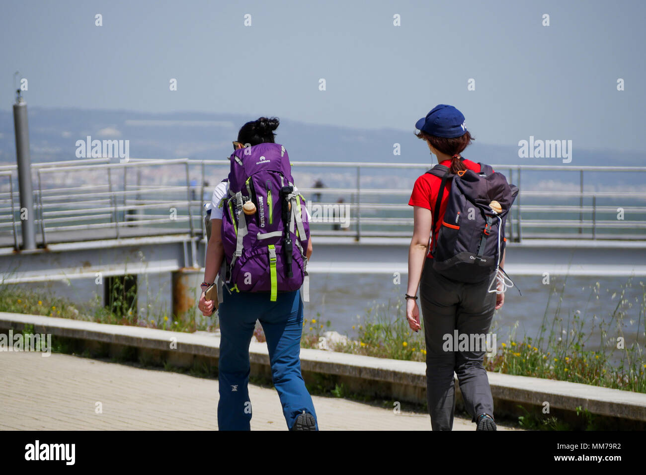 Due pellegrini di Santiago de Compostela a piedi lungo il Tago banca, nei pressi di Ponte Vasco de Gama,, Parco delle nazioni, Lisbona, Portogallo Foto Stock