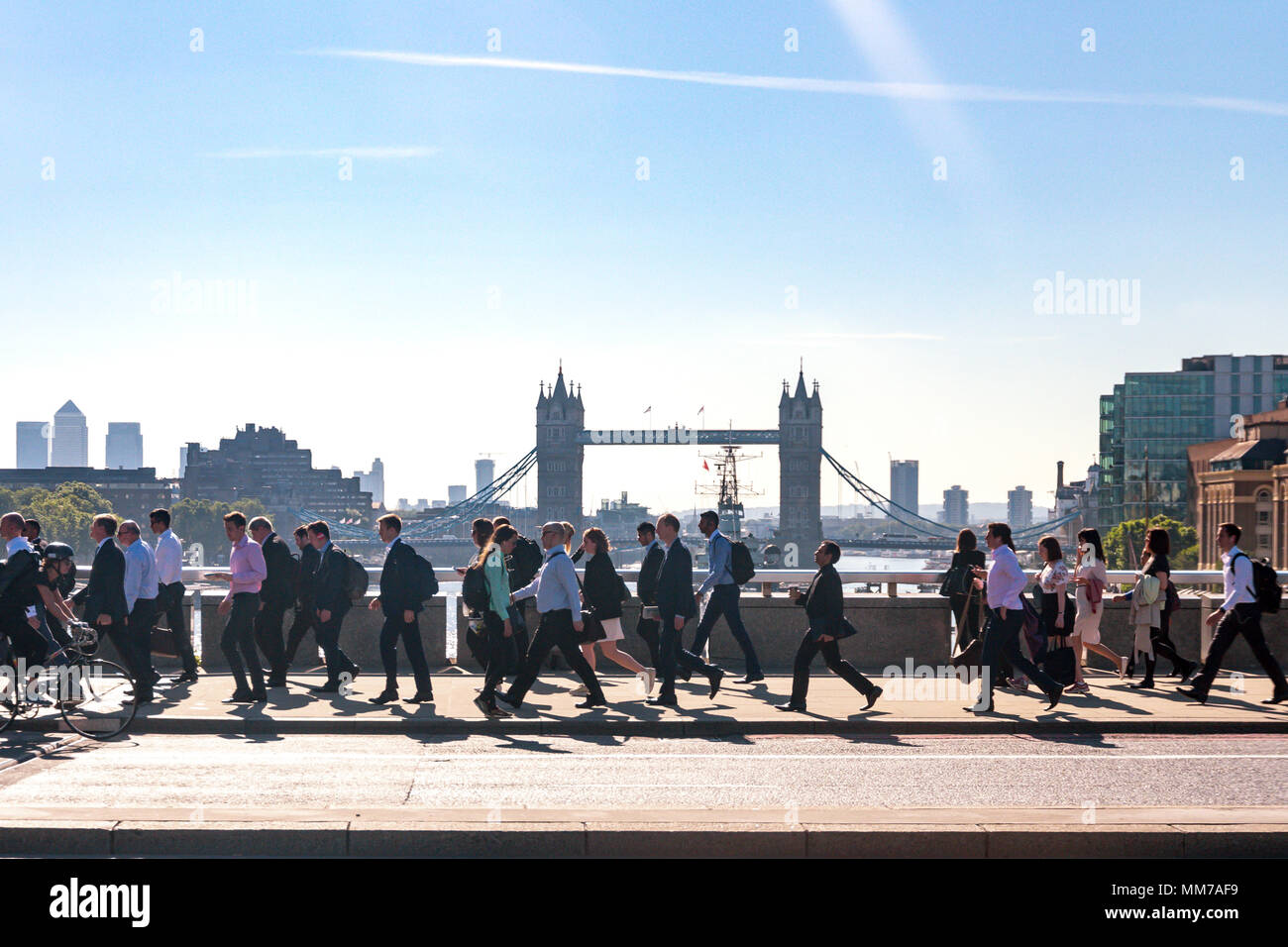 Mattina pendolari a Londra a piedi per lavorare attraverso il London Bridge con il Tower Bridge in background Foto Stock