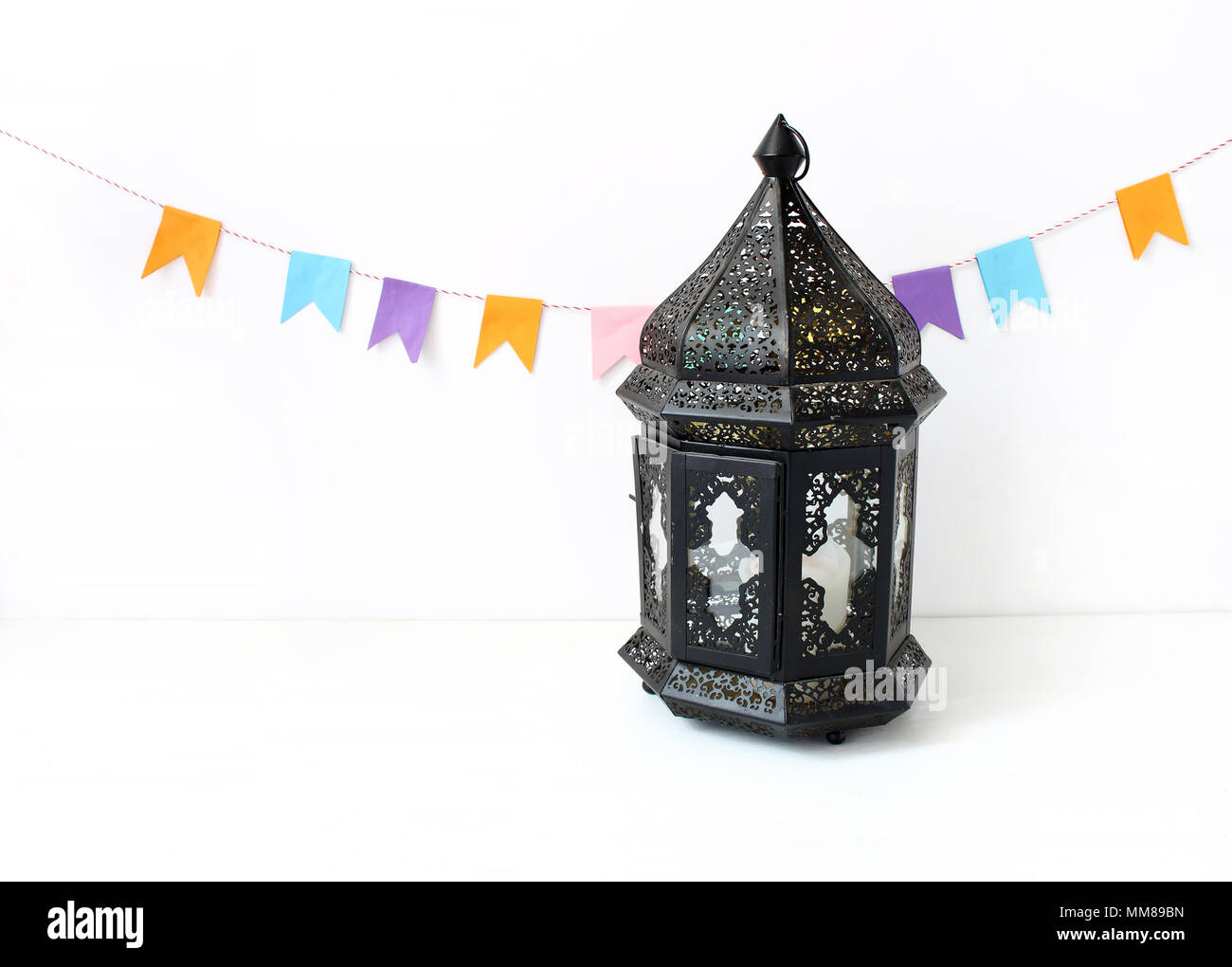 Ornamentali marocchino scuro, arabo lanterna sul tavolo bianco. Decorazione di partito, stringa di carta colorati bandiere. Biglietto di auguri per vacanza musulmana del Ramadan Kareem. Sfondo di festa. Foto Stock