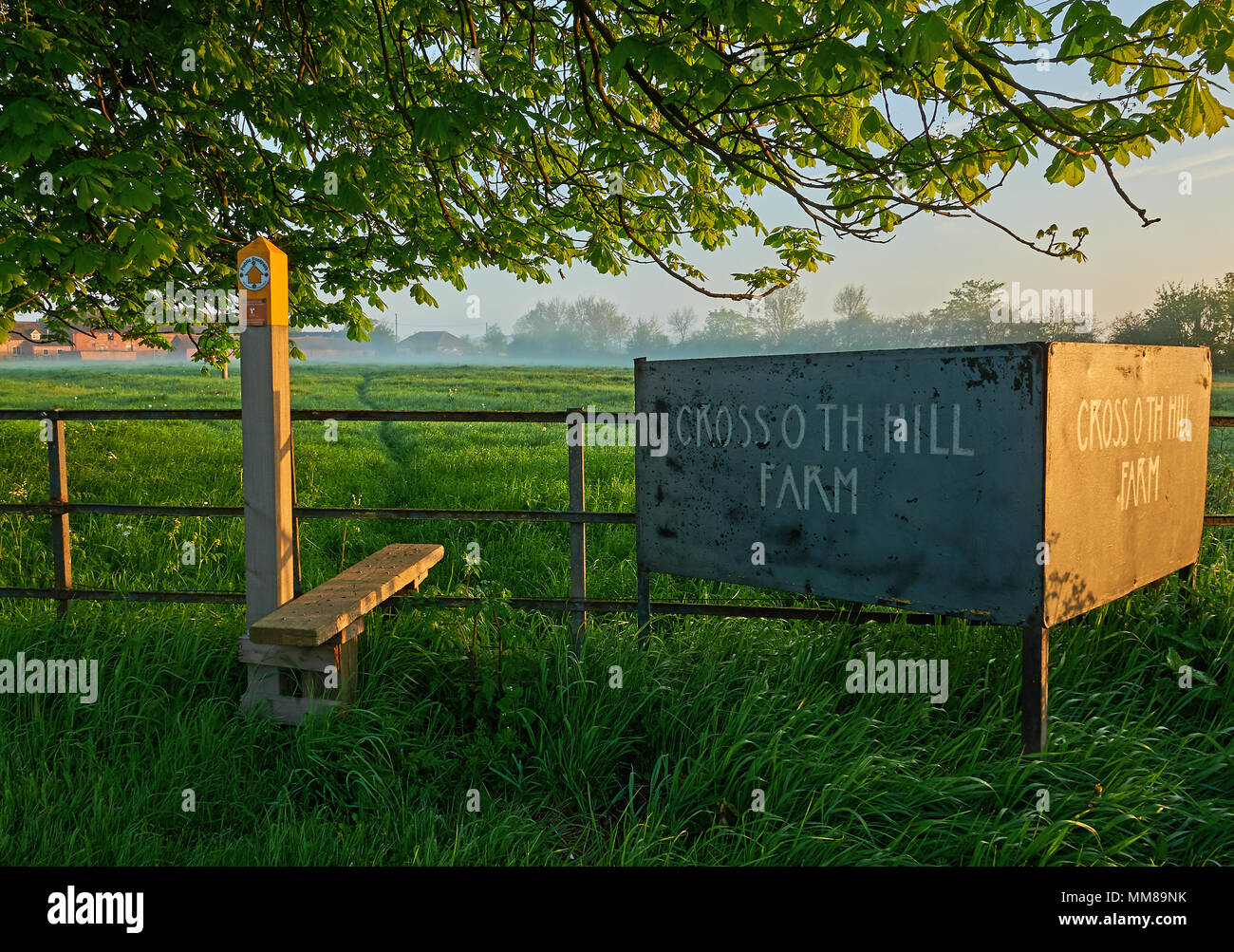Sentiero pubblico e stile su una recinzione metallica con un segno di fattoria in Engalnd rurale Foto Stock