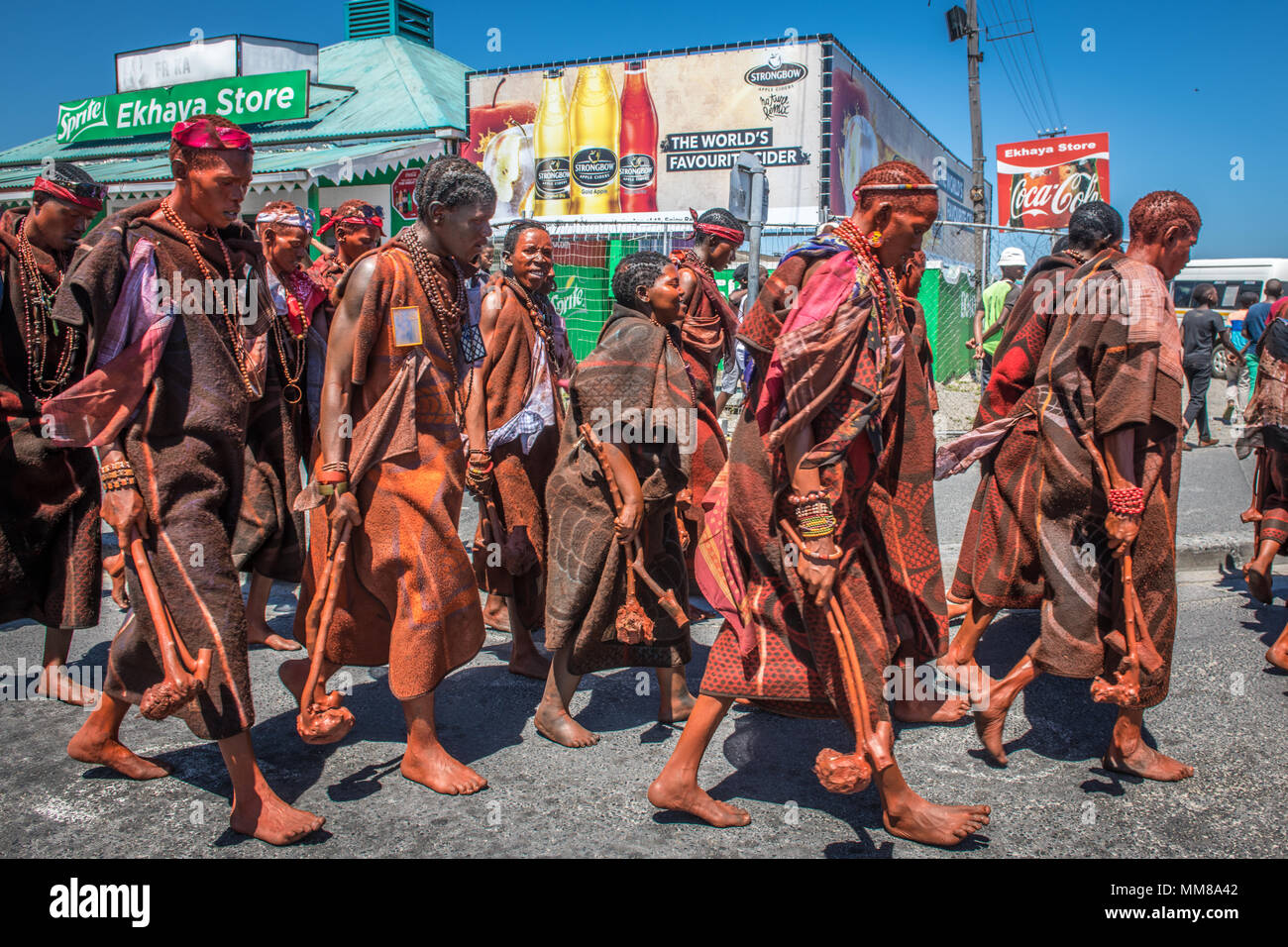 Gruppo di Basotho uomini a piedi attraverso un township come parte di una cerimonia di circoncisione Foto Stock