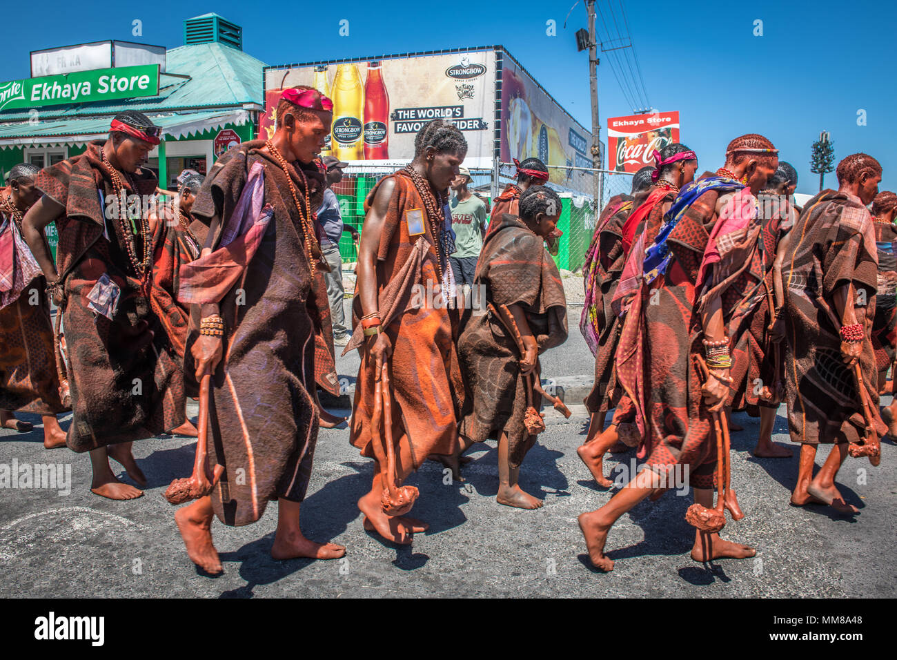 Gruppo di Basotho uomini a piedi attraverso un township come parte di una cerimonia di circoncisione Foto Stock