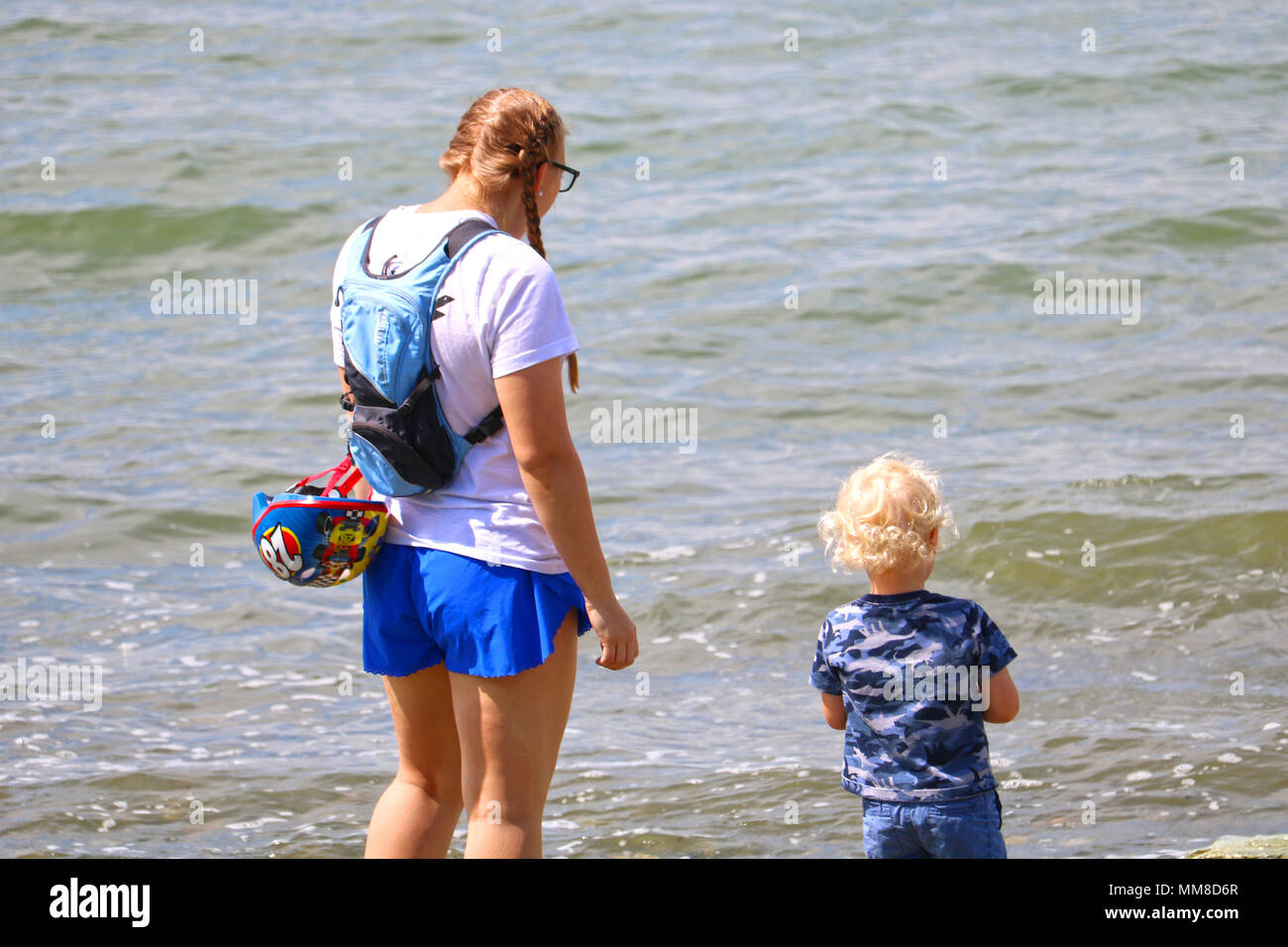 Madre e figlio giovane permanente al bordo delle acque di Boulevard Park di Bellingham, Washington, Stati Uniti d'America. Foto Stock