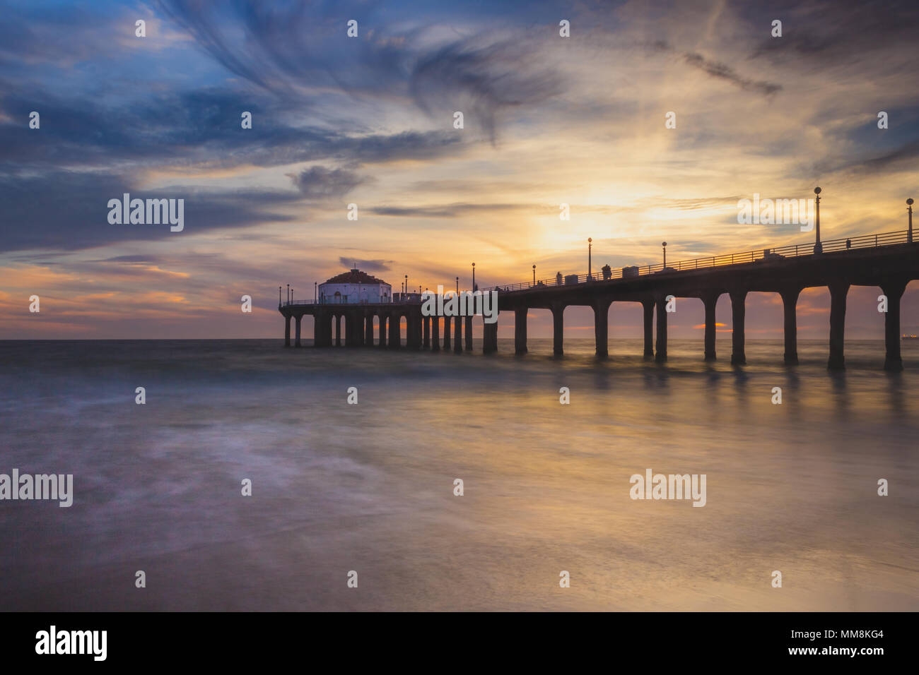 Lunga esposizione shot colorata del Cielo e nubi su Manhattan Beach Pier al tramonto con regolare lavaggio onde sulla spiaggia, Manhattan Beach, Californi Foto Stock